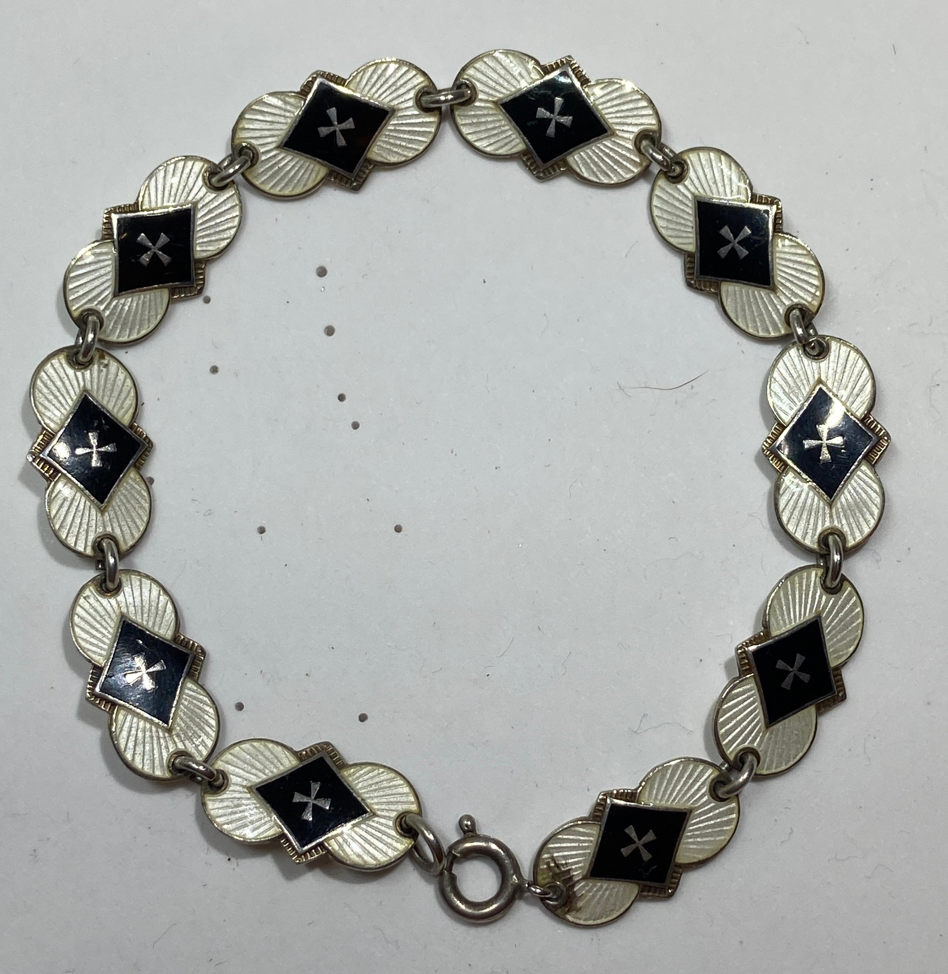 Wonderfully detailed sterling silver link bracelet with exquisite detailed black and cream baked enamel overlay. The total length measures 7 inches. width measures 3/8 of an inch. Maker's mark etched on the back. Made in England.
