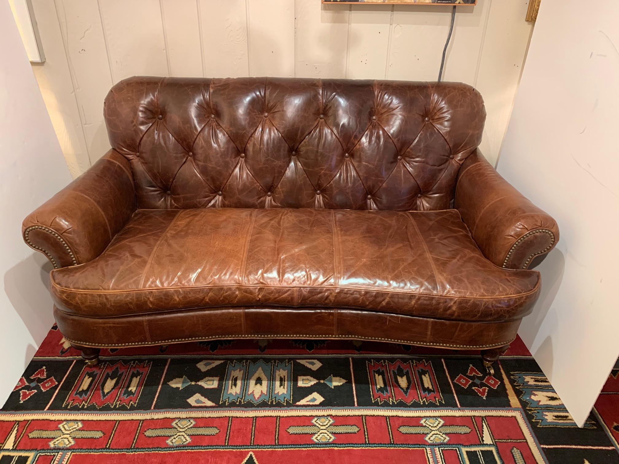 Delicious traditional supple brown tufted leather loveseat having mahogany turned legs on brass casters and brass nailhead details.
Measures: Seat depth 22
Arm height 24.5.