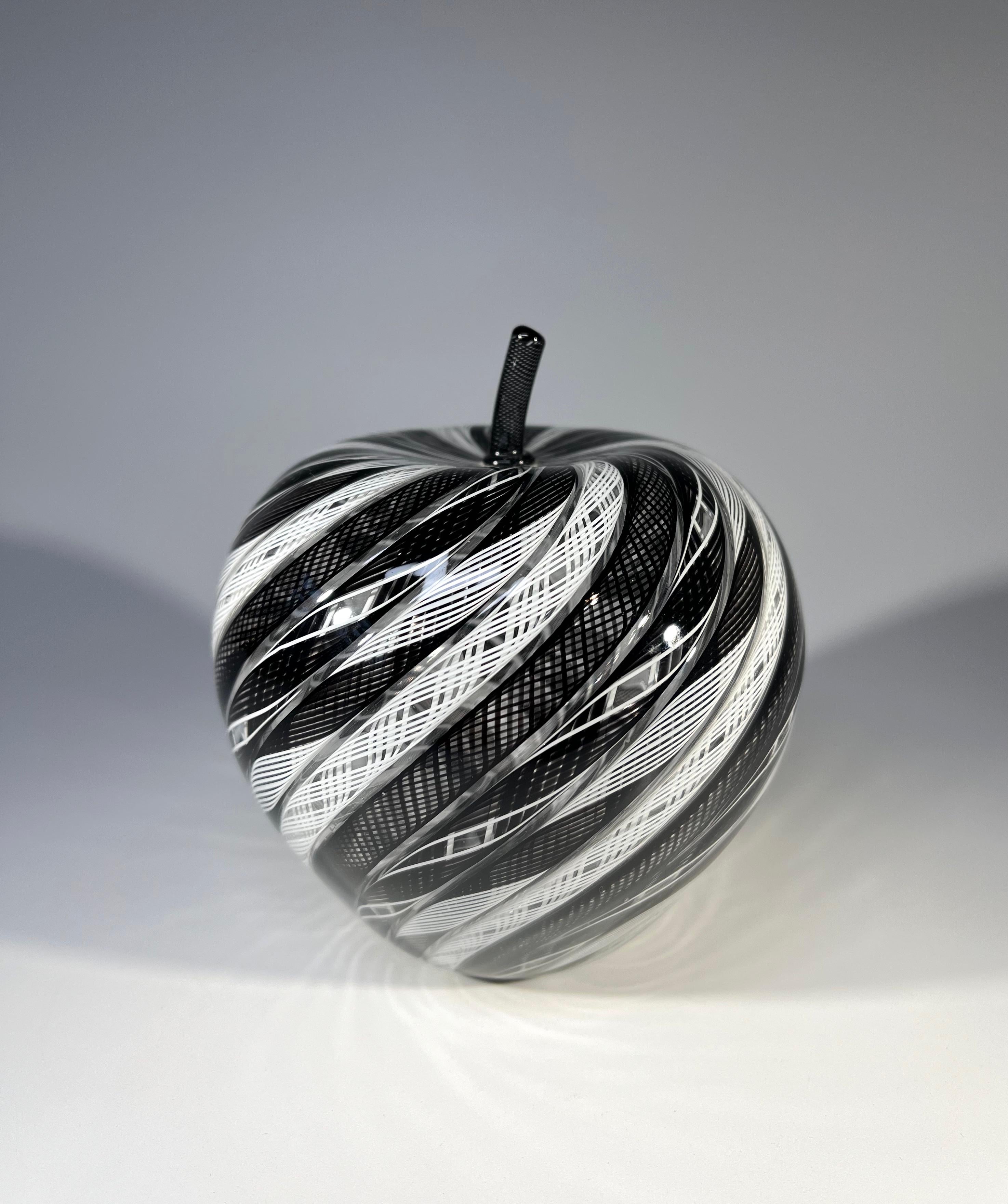 Verschlungene, mundgeblasene schwarze und weiße Zanfirico-Glasstangen, die in hervorragender Weise zu einem verlockend köstlichen Glasapfel verarbeitet sind 
Hergestellt von dem bekannten Glaskünstler Mike Hunter vom Twists Studio in