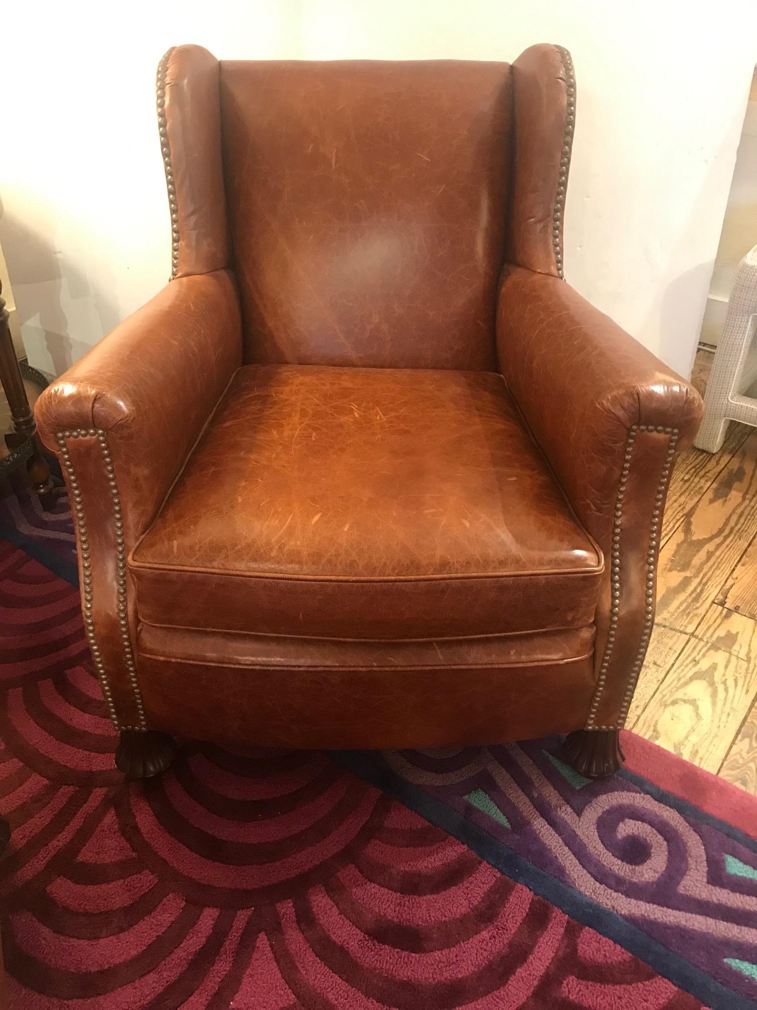 Supple brown leather classic club chair and tufted ottoman, having brass nailhead detailing and beautiful carved wood feet. Label reads William Alan.

Measures: Seat 23 D x 16.75 H
Arm 23 H
Ottoman 22.75 W x 16 D x 12 H.
 