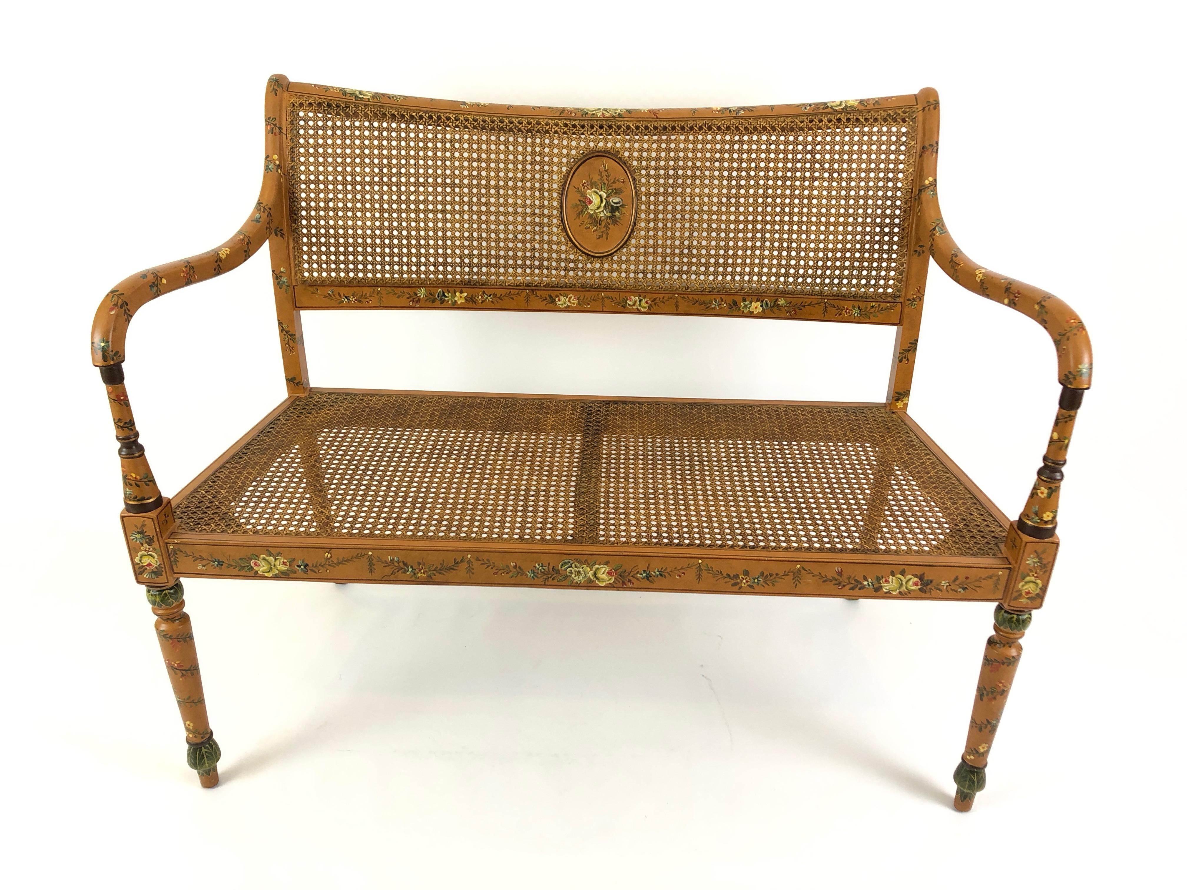 Beautifully hand painted wood and caned loveseat having graceful curved arms, pretty central oval medallion front and back and wonderful details such as leaves adorning the curved ends of the legs. Custom neutral upholstered cushion