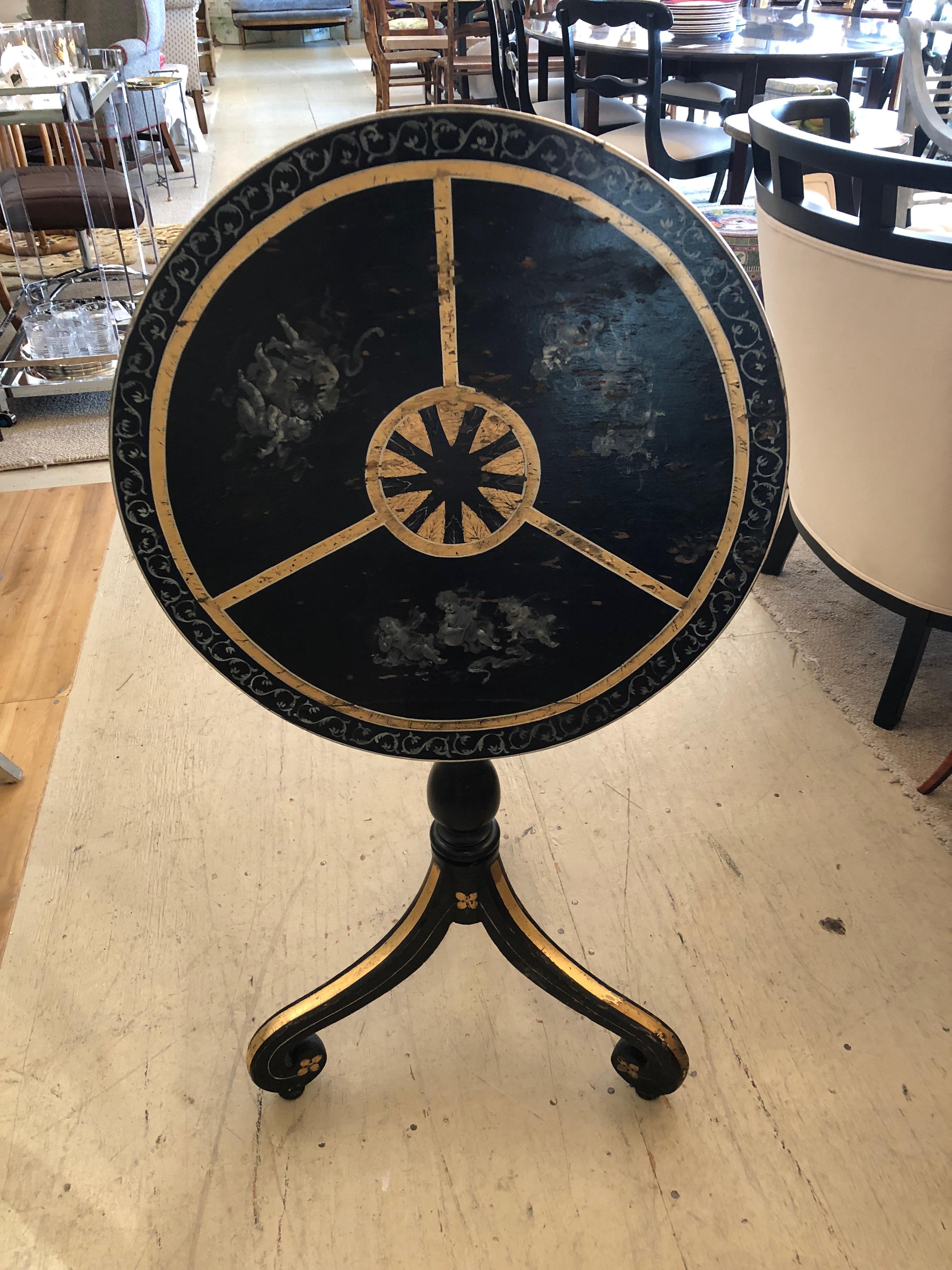 Beautiful round flip-top vintage table having original black, gold and grey paint, intentionally left distressed on top. Wonderful subtle paintings of putti and gorgeous decorative gold central mandala. When flipped upright 38.5 H.