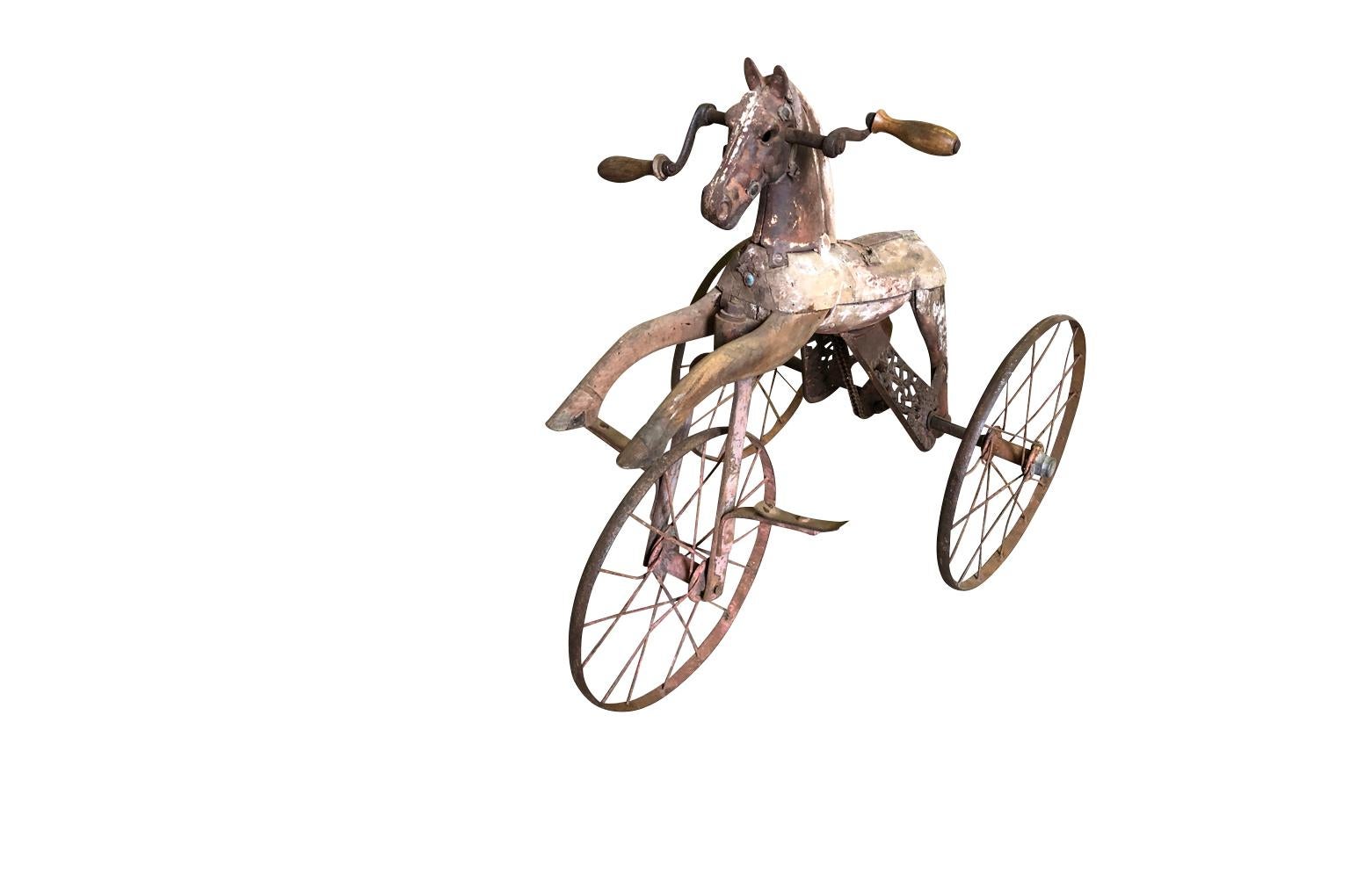 A very charming early 19th century child's horse tricycle in wood and iron. A wonderful accent piece.