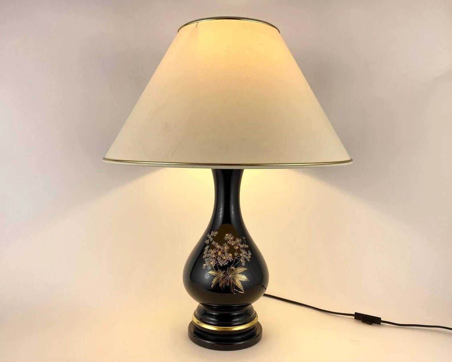 Large Vintage French table lamp combine functionality with beauty and sculptural perfection. In this design of classic shapes, the base of a vase decorated with gilt and white colored branch with flowers and leaves.

The contrast between the black
