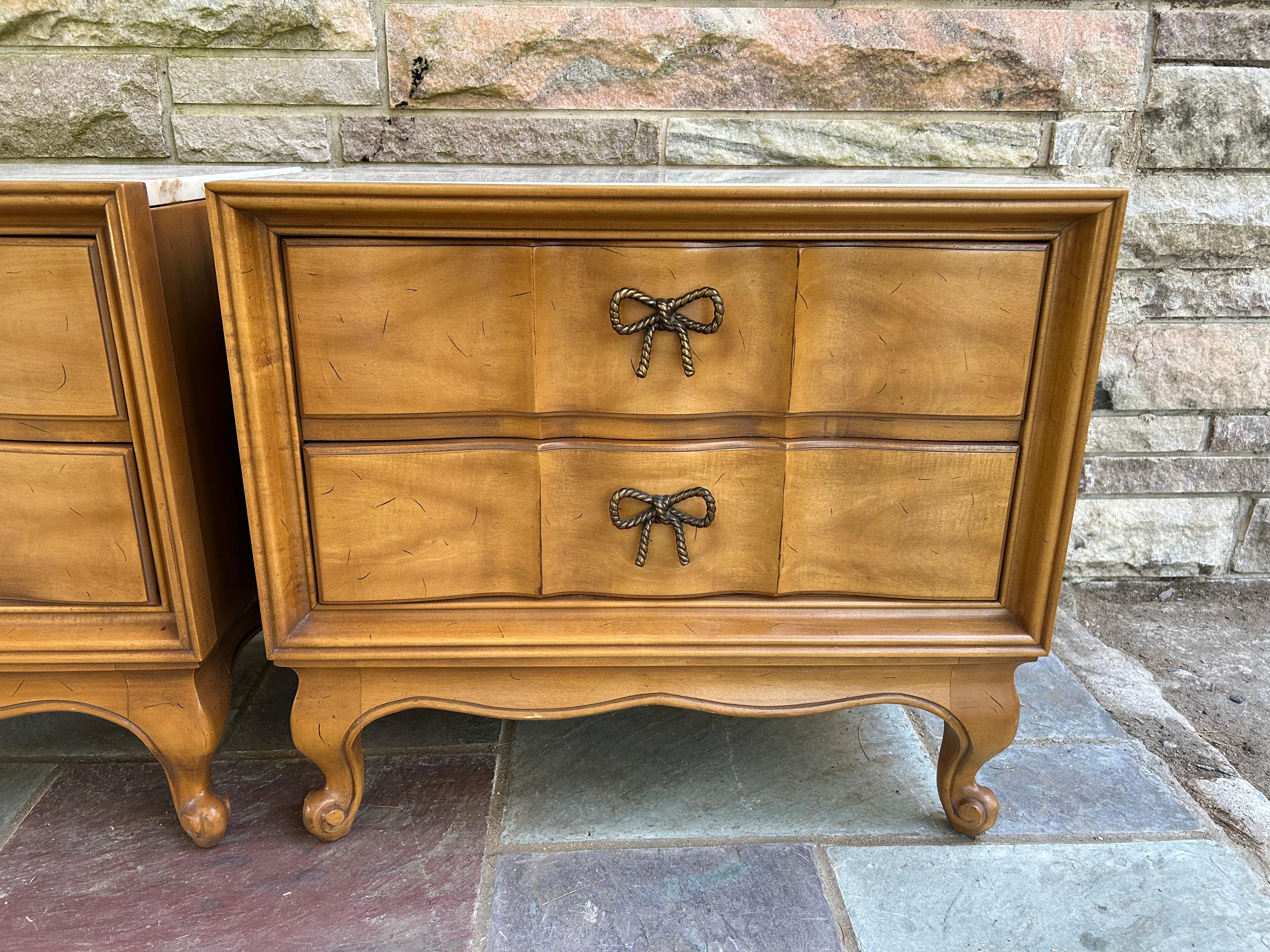 Lovely pair of French Provincial marble top night stands made by American of Martinsville.  We just love the classical styling with the charming brass bow pulls.  These delightful stands are super high quality made with solid fruitwood cases and