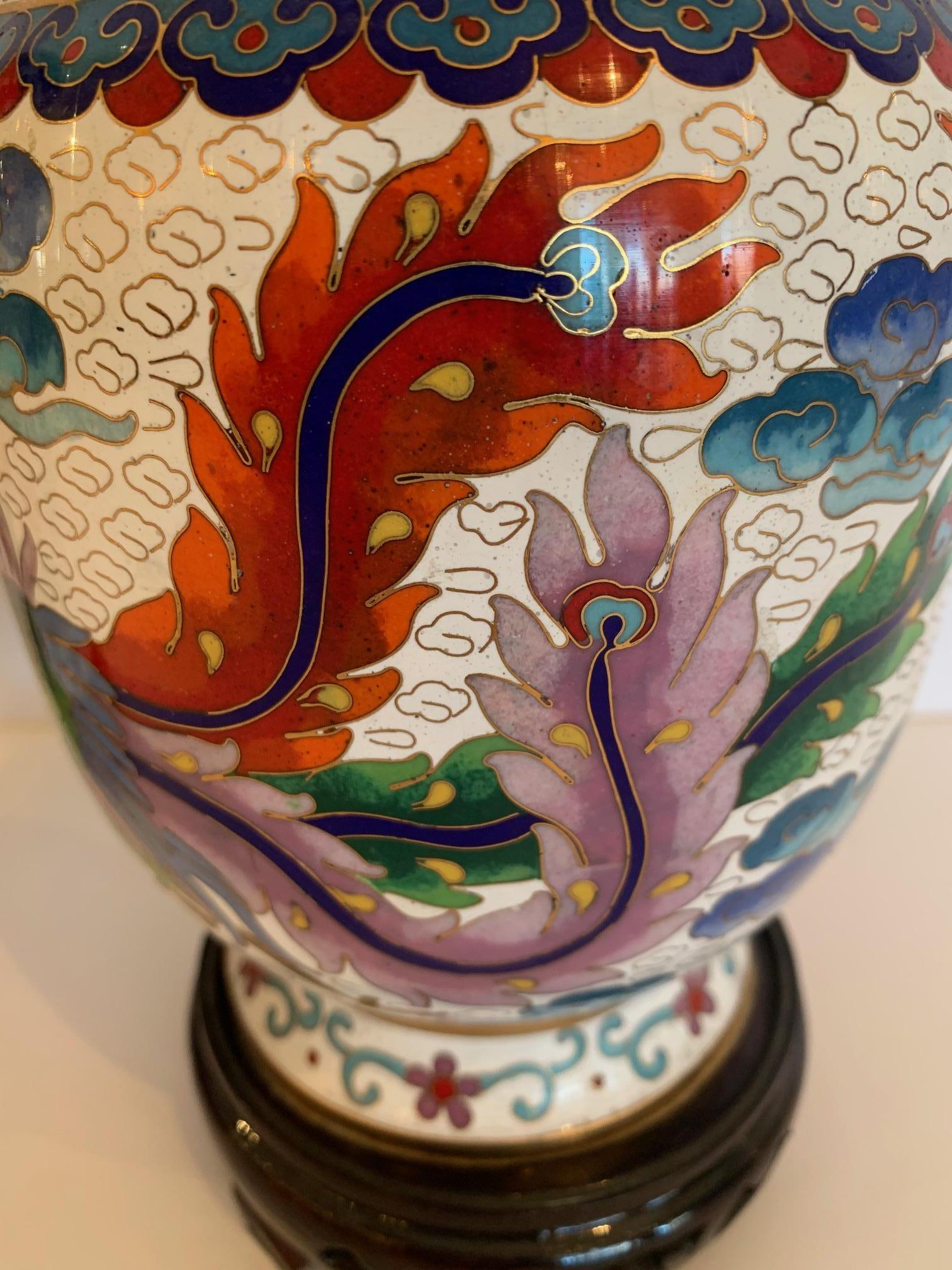 Gorgeous eye-catching pair of cloisonné enamel vases having phoenix birds, dragons and meticulous decoration in green, blue, purple, red, turquoise, yellow and white. There are gilded highlights and the interior of the vase is gold. Bases are