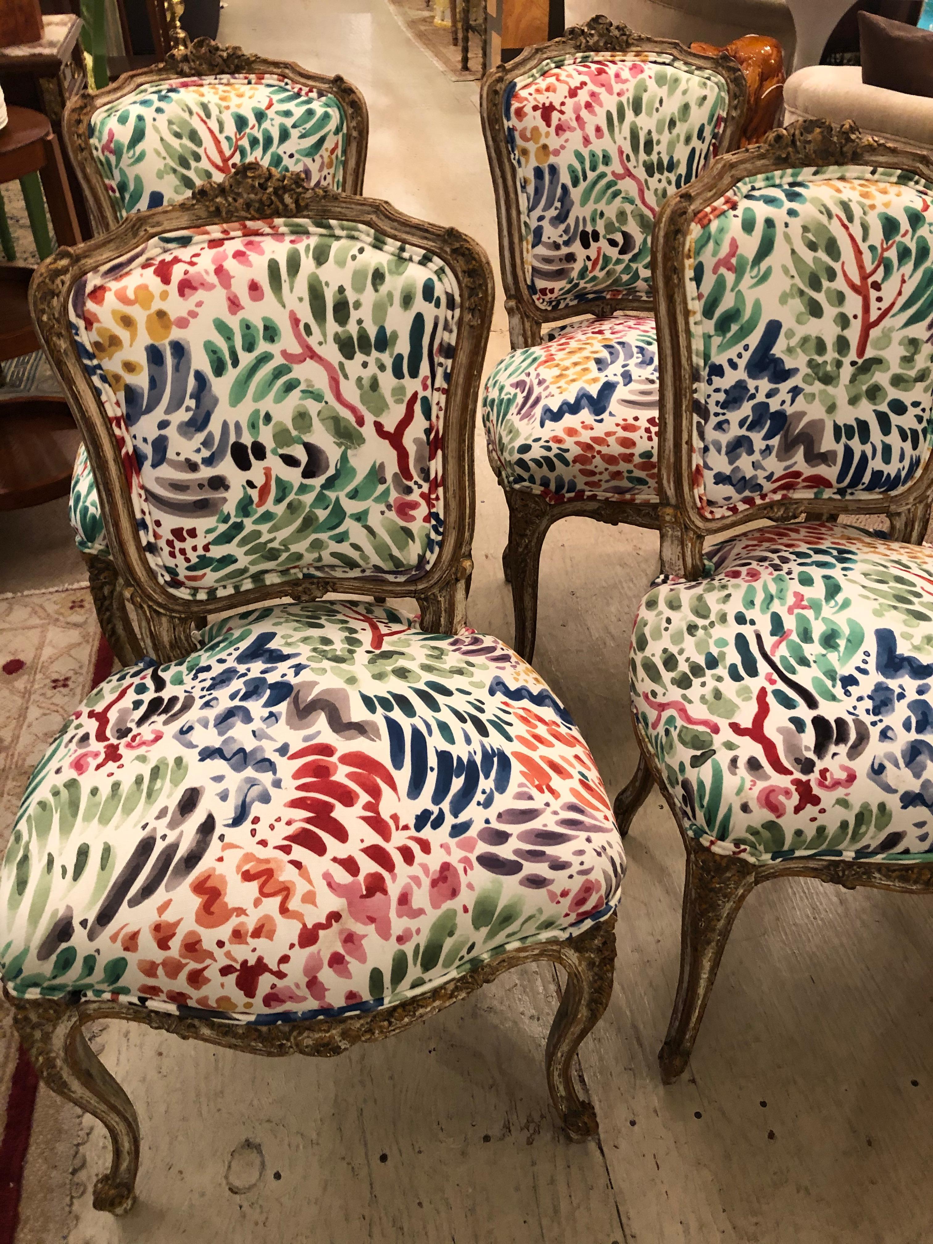 A chic adorable set of 4 Classic Louis XVI distressed painted carved wood side dining chairs, newly updated in a fun abstract pattern upholstery. Fabric has splashes of magenta, fushia, lime green and purple against a cream background. Wood has