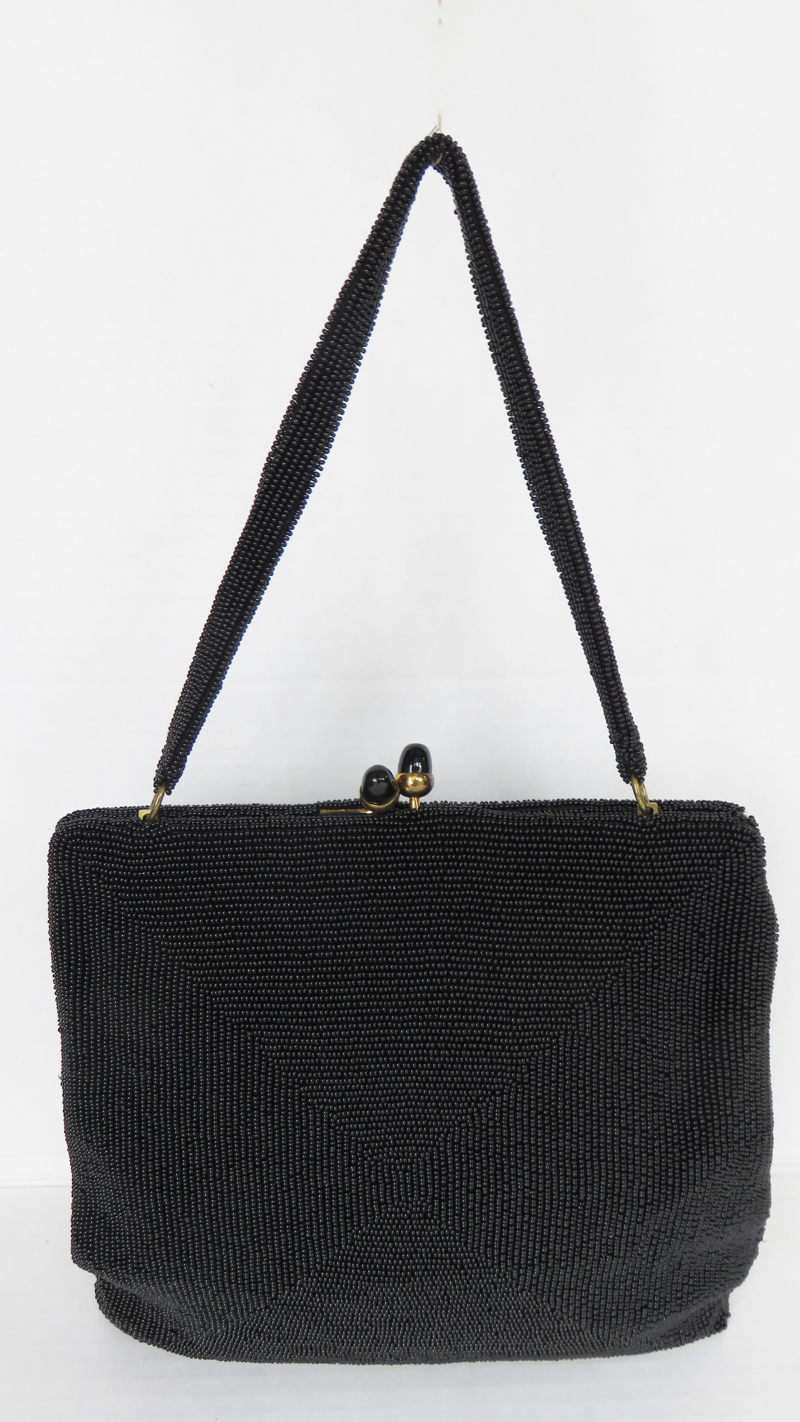 A beautiful fine black glass beaded by Delill in and intracate square pattern. It has a top handle, top black glass button closure and is silk lined with an inner pocket.

Height  8