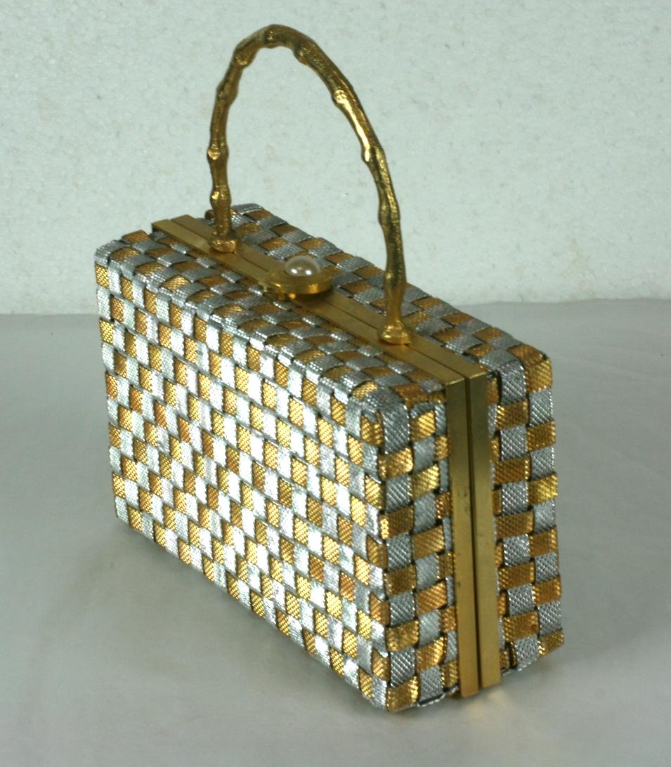 Charming Delill Woven Silver and Gold Box Bag from the 1960's. Woven metal strips create a textile, with abstract gold bamboo handle. Lined in metallic copper faux leather. Pearl clasp closure.  
Made in Italy 1960's. 
6