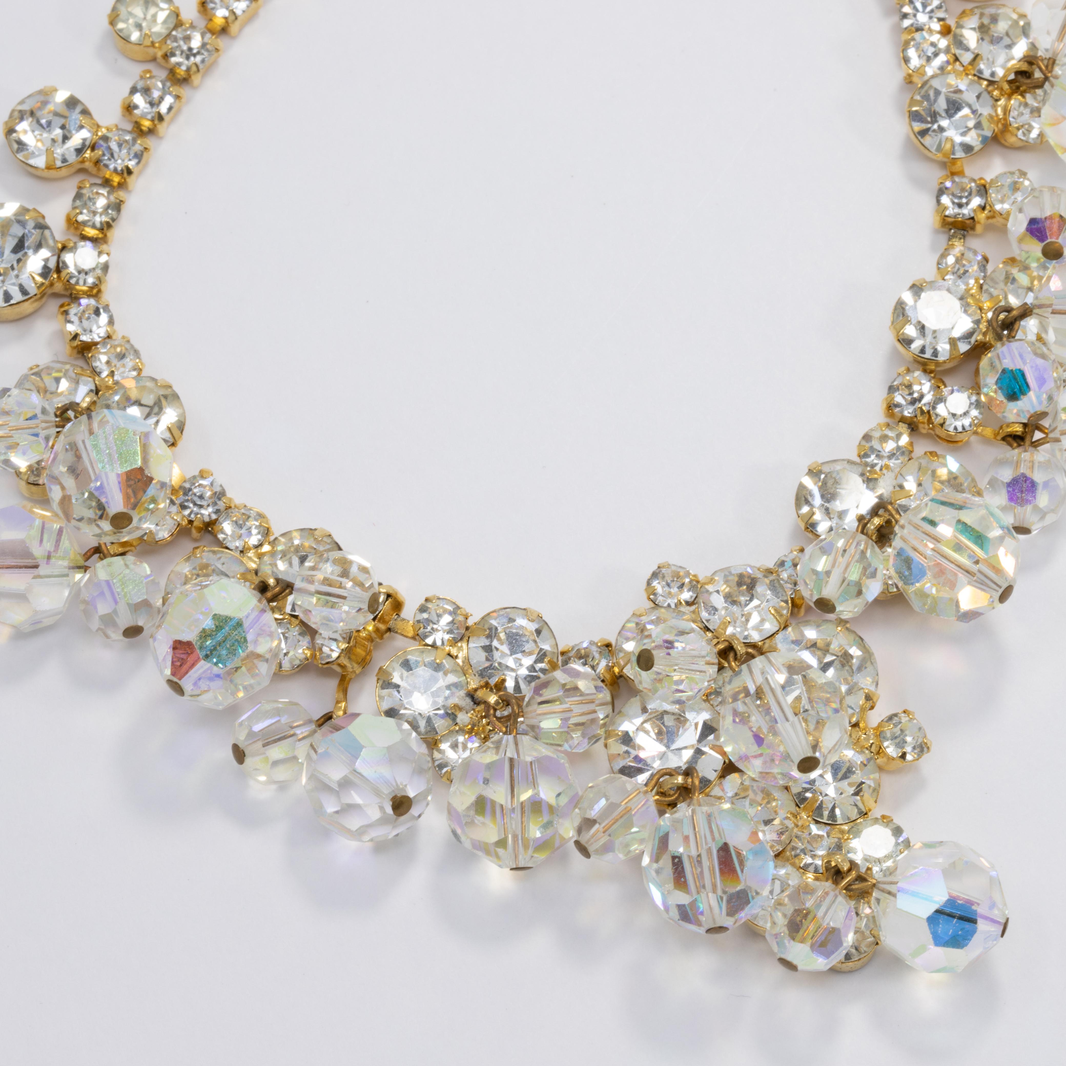 Enticing  rhinestones are the foundation for this amazing display of aurora borealis faceted dangles layered throughout this fabulous necklace, link bracelet, floral branch brooch, and cluster clip earrings parure. From the Juliana line by DeLizza