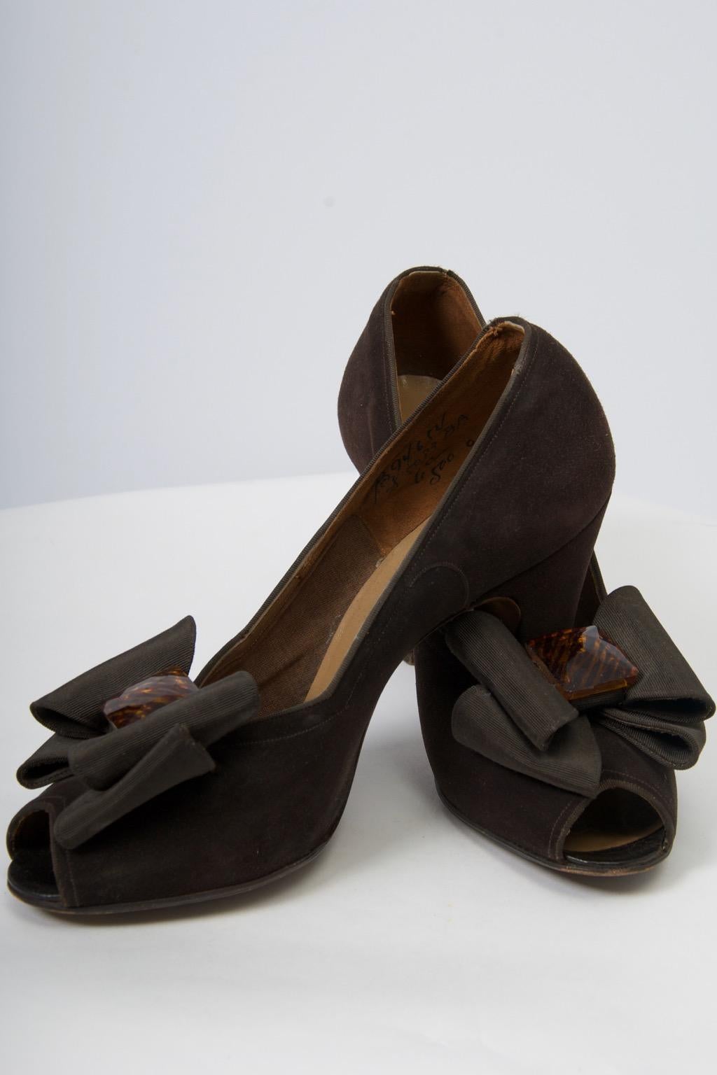 Sophisticated and elegant late 1940s-early 1950s brown suede pumps featuring an open toe, chunky heel, and large grosgrain bow centering a tortoise ornament. Made by Delman for Bergdorf Goodman. From an estate of European royalty. Marked size 6C,