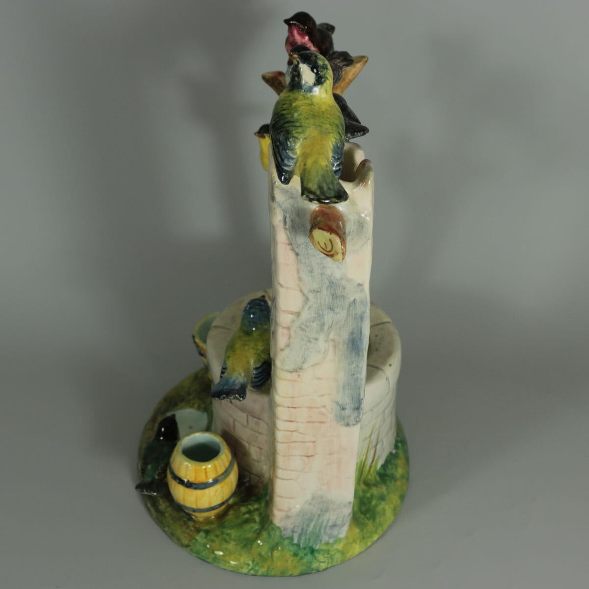 Delphin Massier French Majolica centerpiece which features seven colorful garden birds, perched around a wishing well. Coloration: cream, yellow, green, are predominant. The piece bears maker's marks for the Delphin Massier pottery. Book