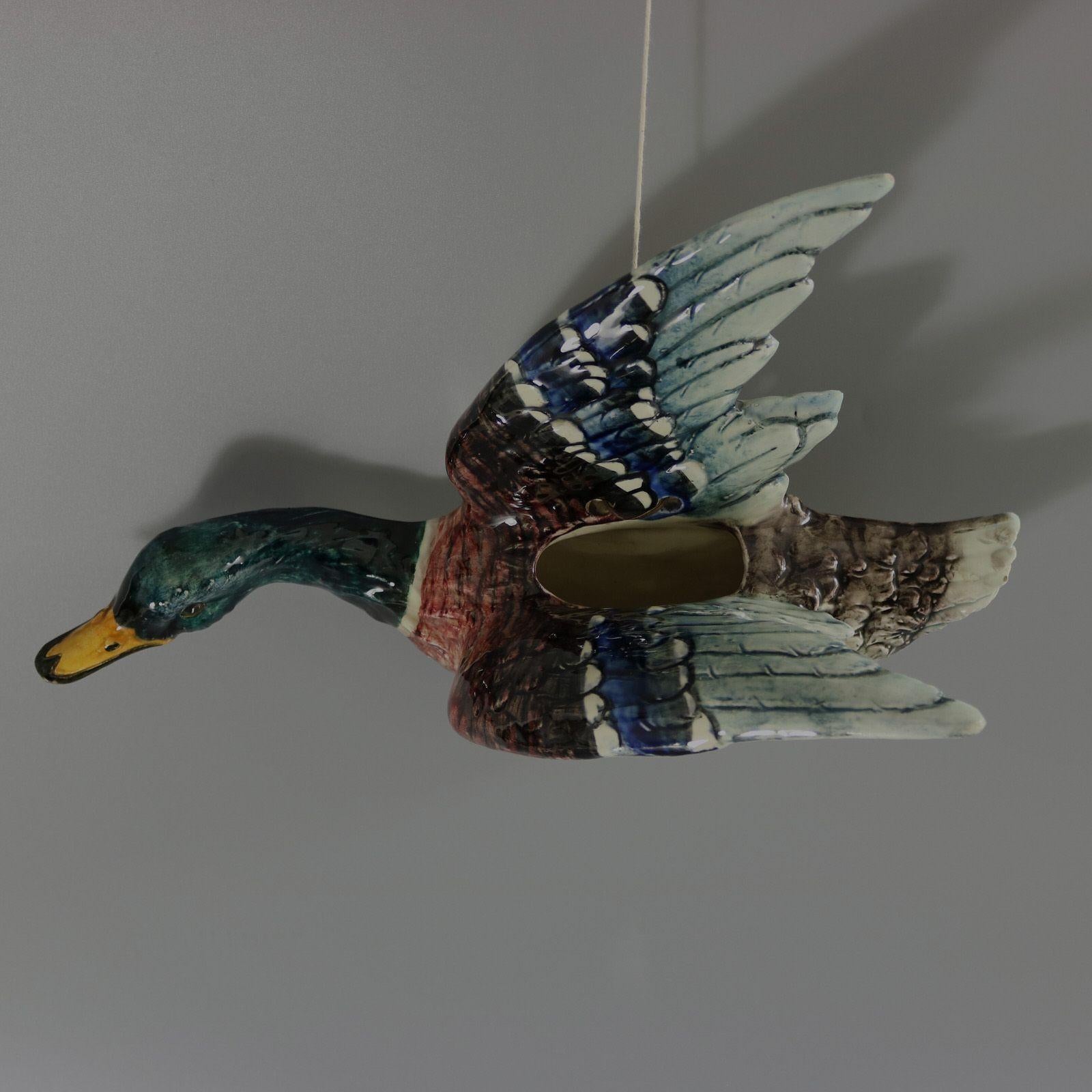 Delphin Massier Majolica wall pocket which features a duck (mallard) in flight, with wings raised. Colouration: white, pink, teal blue are predominant. The piece bears maker's marks for the Delphin Massier pottery.