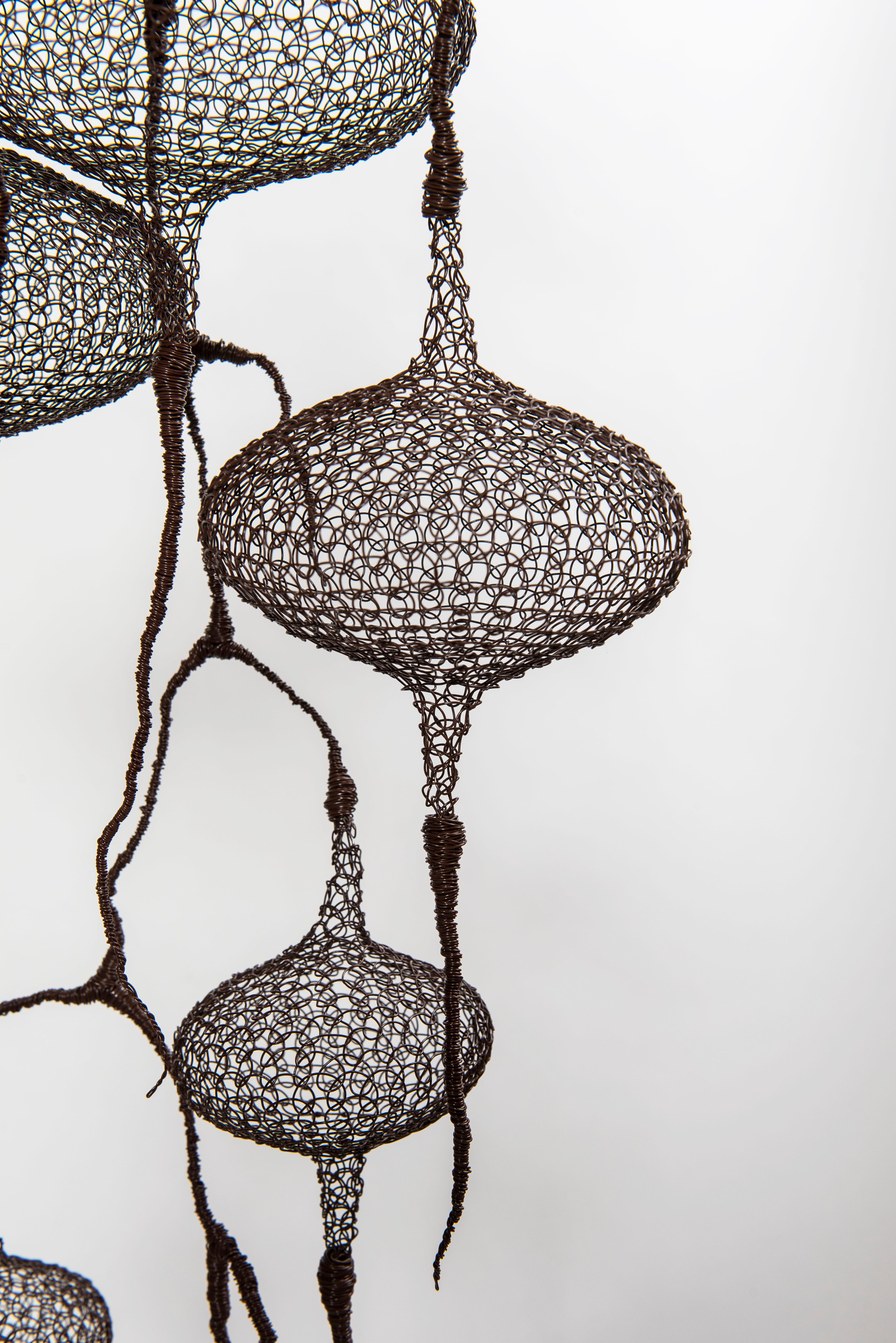 This airy sculpture created from a brown iron wire by Delphine Grandvaux depicts 10 hand-knitted round-shape volumes being linked in a way of  