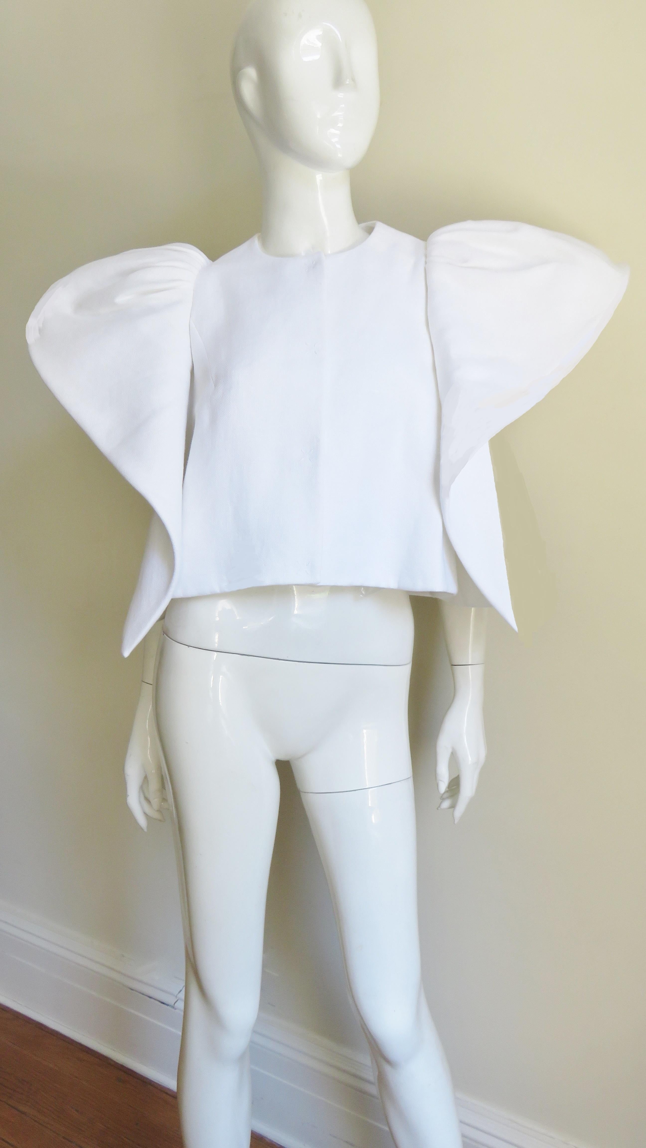A fabulous sculptural white linen jacket from Deplozo. It has large silver dome front closing and fabulous panels encircling the armholes flaring at the the shoulders and is lined in fine white polished cotton.
Fits sizes Extra Small, Small, Medium.