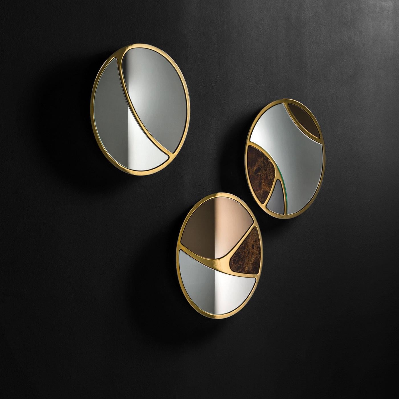 A combination of refined materials in a unique design, this mirror features three sections, elegantly divided by a laser-cut metal frame with a bronze finish: one of Emperador marble, one in smokey gray and the larger section in clear mirror. The