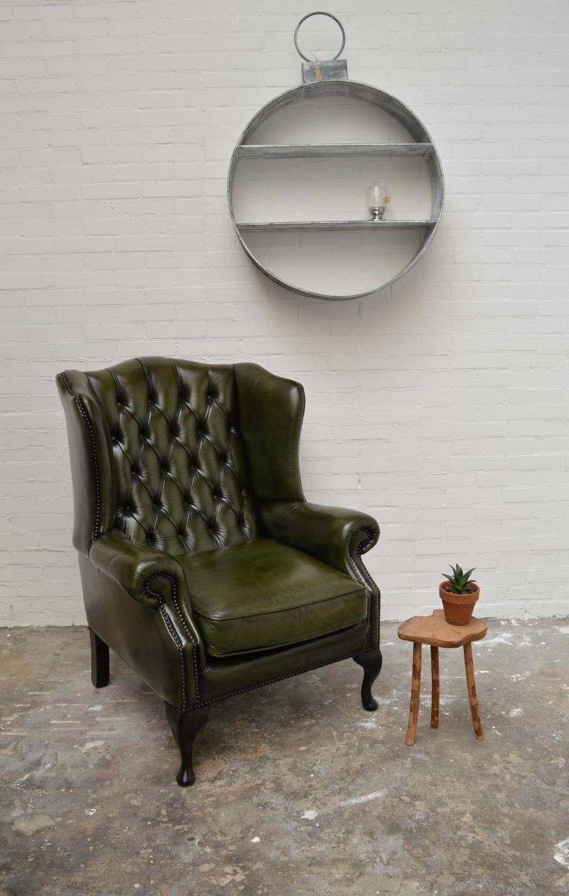 Nice authentic Chesterfield wingchair.
Cowhide leather in antique olive green rub-off standard finish. Nice good state and new piping on the cushion so it can go for many years again.

Inside (frame) checked and cushion refilled. Further no