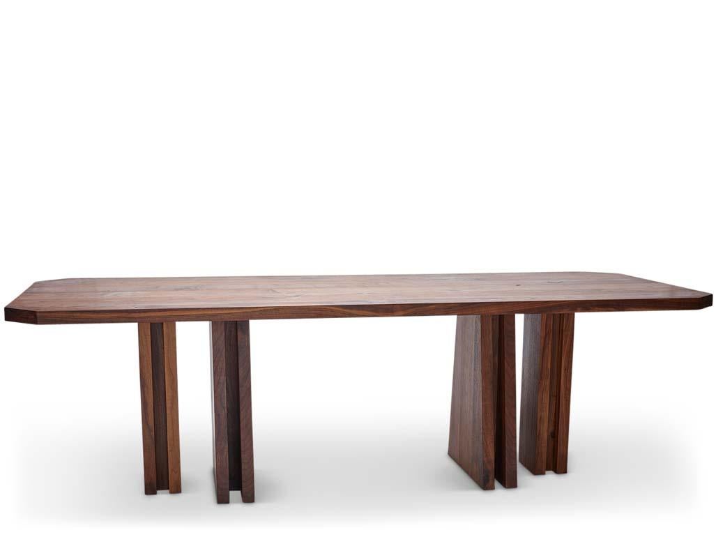Inspirée par le brutalisme et Carlo Scarpa, la table à manger Delta est à la fois monumentale et ludique. Delta fait référence aux formes triangulaires des pieds et à l'espace négatif des coins du plateau. 