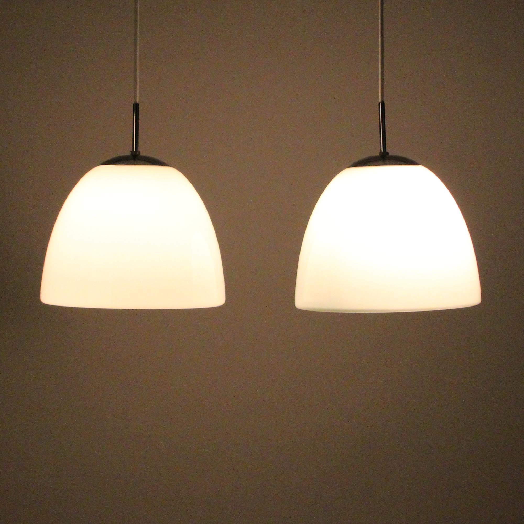 Delta Klokkependel or bell pendant - produced by Louis Poulsen in 1967. Pair of Classic Danish midcentury glass lights in excellent vintage condition.

A beautiful opal blown glass shade with a bell-like shape, closed bottom and chrome-plated top.