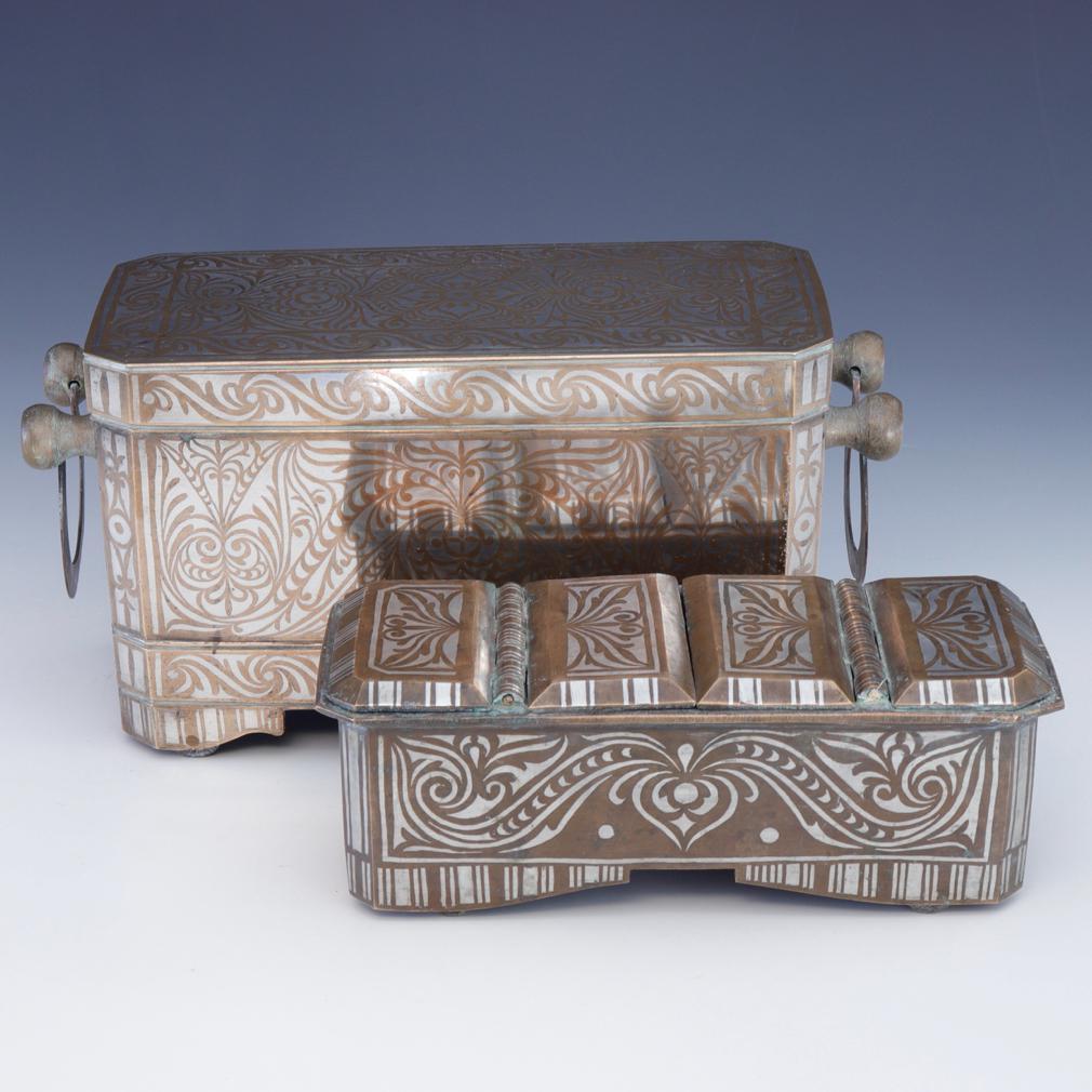 Two bronze rectangular boxes decorated with symmetrical silver inlay in the tendril vine pattern referred to as “the okir pattern”,  a traditional design for the Maranao people. This is a large and heavy set with each box complete with wheels. The