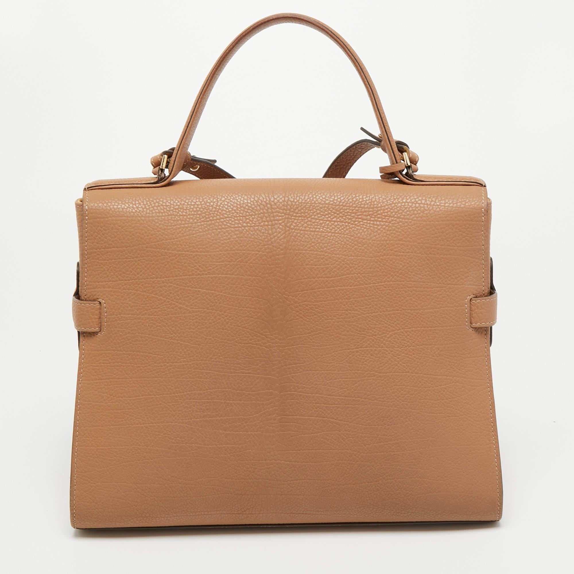 This handbag by Delvaux has a structured silhouette and elaborate interiors to create a classically chic look. This alluring and beautifully fashioned leather bag is surely a must-have. It is held by a top handle and crafted to