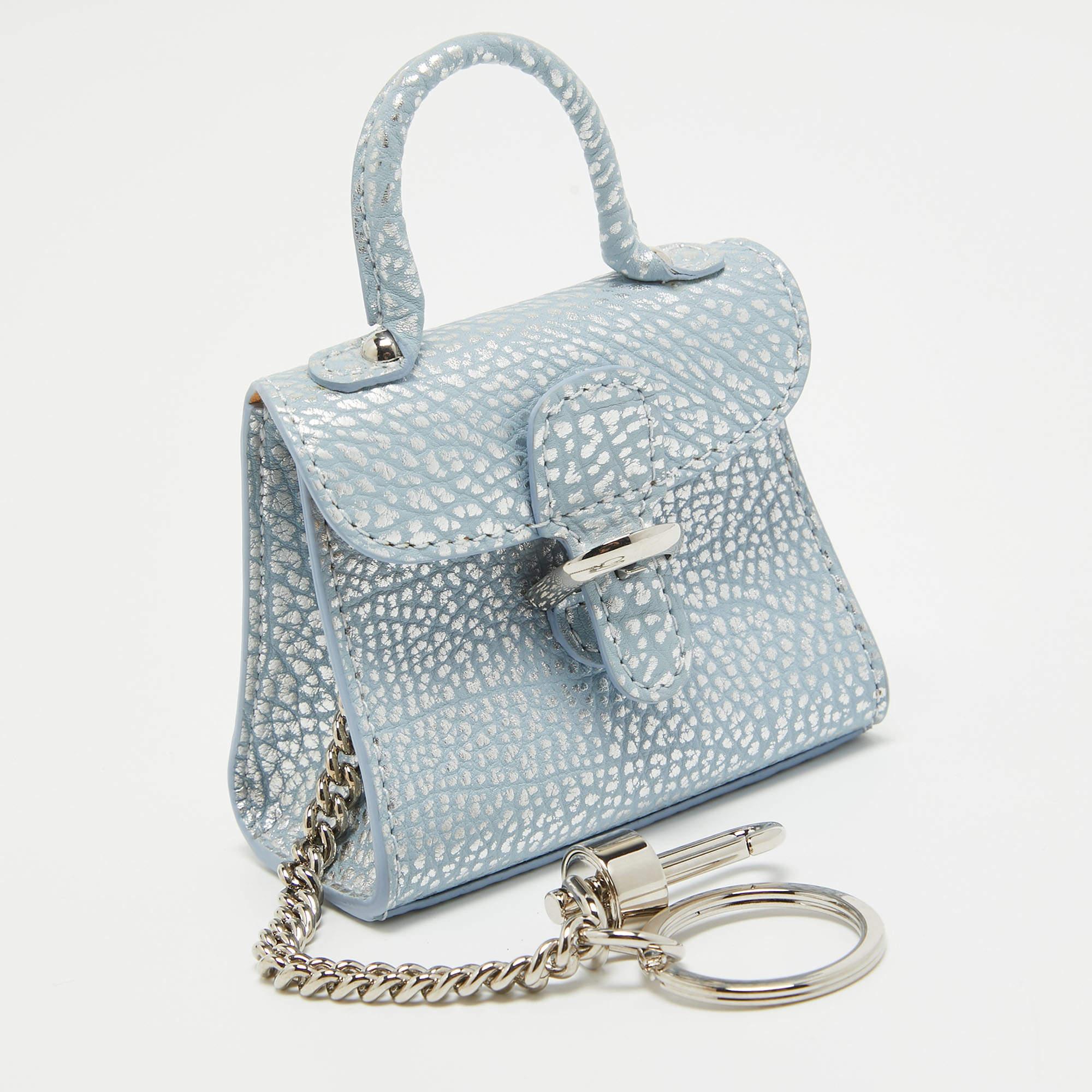 Crafted by Delvaux, the charm exudes timeless style. The supple leather, adorned with silver accents, dances in the light, catching attention effortlessly. A symbol of understated luxury, it adds a touch of refinement to any accessory collection,