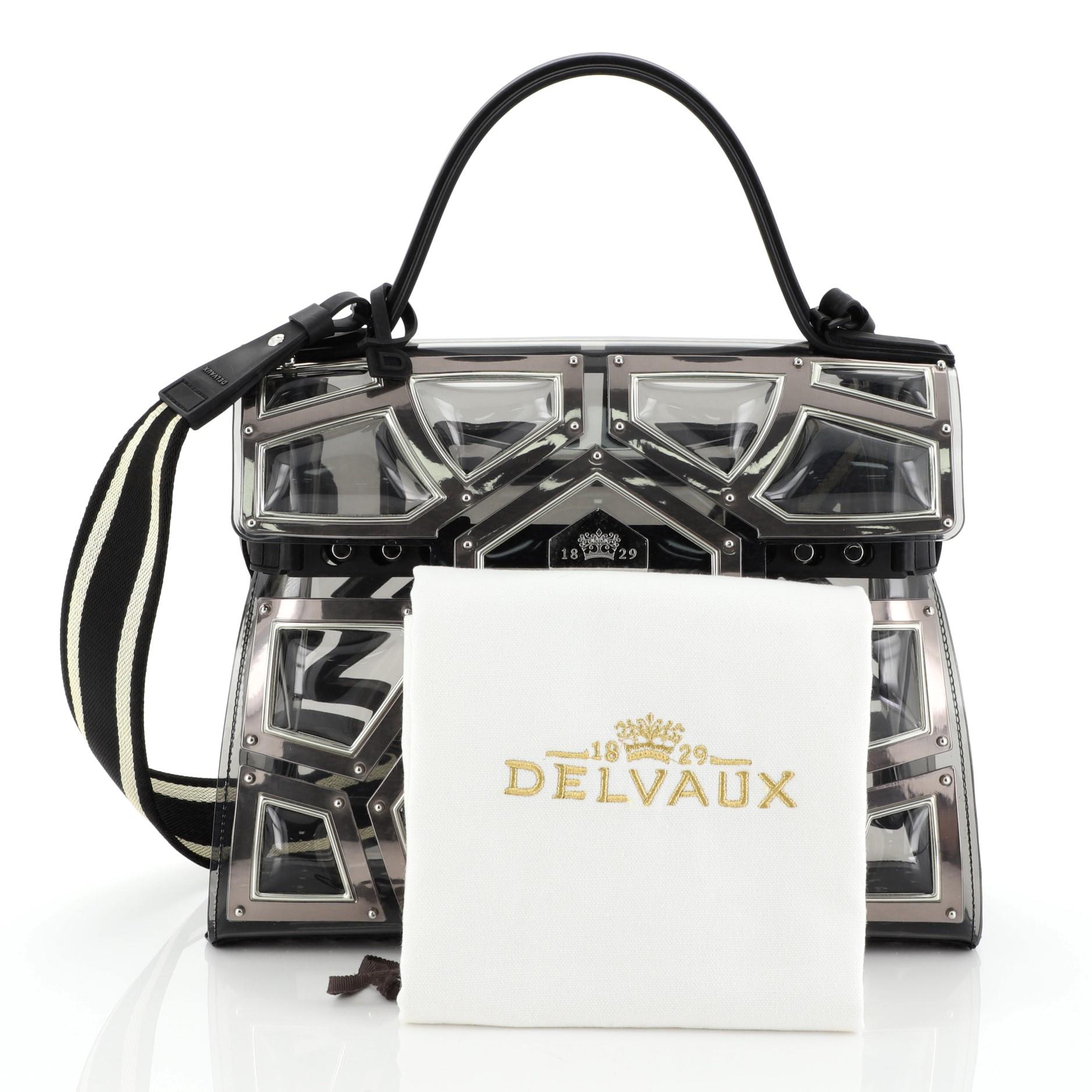 This Delvaux Gladiator Tempete Top Handle Bag Metal Embellished Vinyl GM, crafted in black vinyl framed with metal edging, features a leather top handle, spiked base and silver and gunmetal-tone hardware. Its push-lock closure opens to a black vinyl