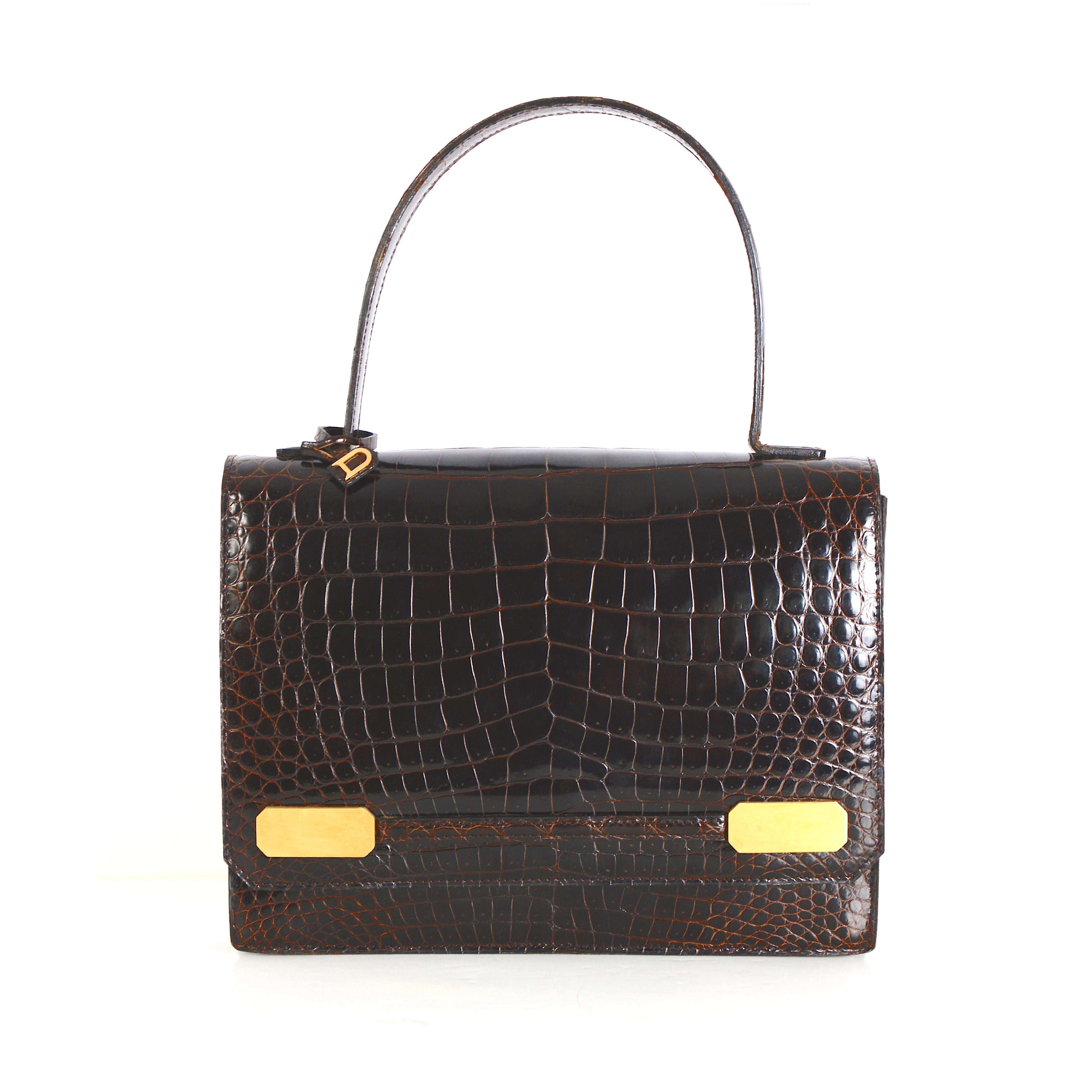 Wir stellen Ihnen diese außergewöhnliche Delvaux-Tasche mit braunem Kroko-Obergriff aus den 1980er Jahren vor.

Lassen Sie sich von der zeitlosen Eleganz dieses außergewöhnlichen Delvaux-Designs verzaubern, einem echten Vintage-Schmuckstück aus den