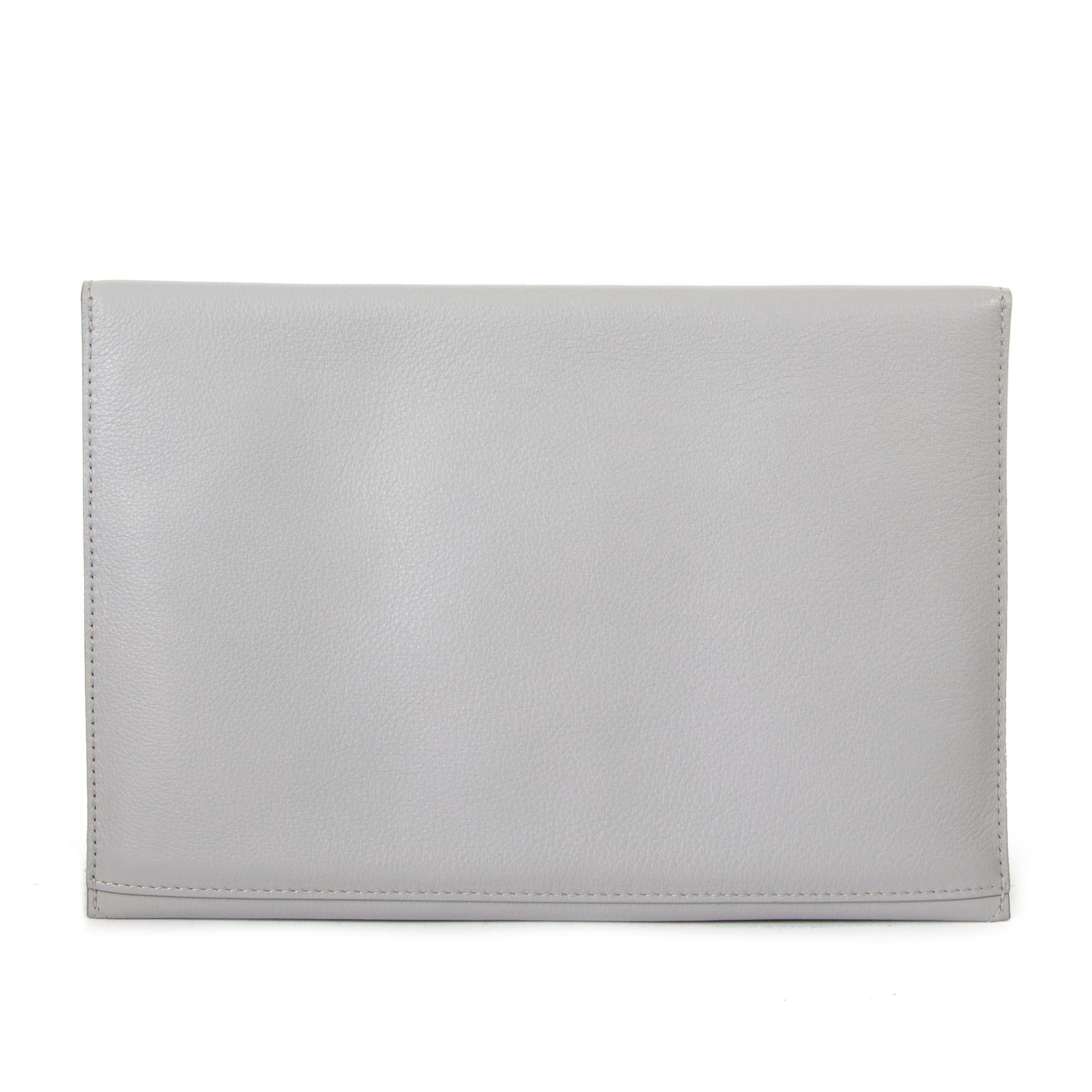 Excellent condition

Delvaux Light Grey Message Clutch

This message clutch is crafted from a light grey leather and has a bright yellow interior. The clutch is styled with a gold toned crown on the front flap. 
It opens with one push lock in the