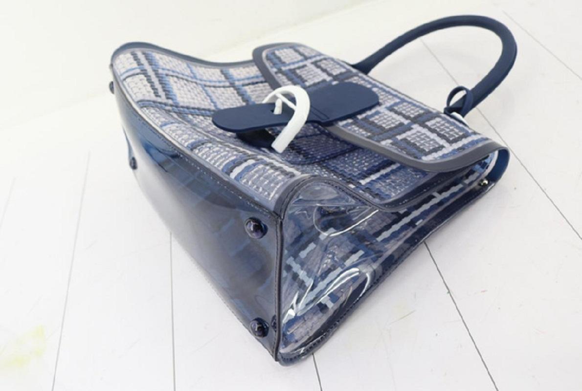 Die Delvaux Brilliant The Dreamer Schultertasche ist aus feinem, strapazierfähigem Vinyl in Weiß und Marineblau mit Gingham-Muster gefertigt. Die Tasche hat einen blauen Henkel, einen optionalen Schulterriemen und weiße Beschläge. Die obere Klappe