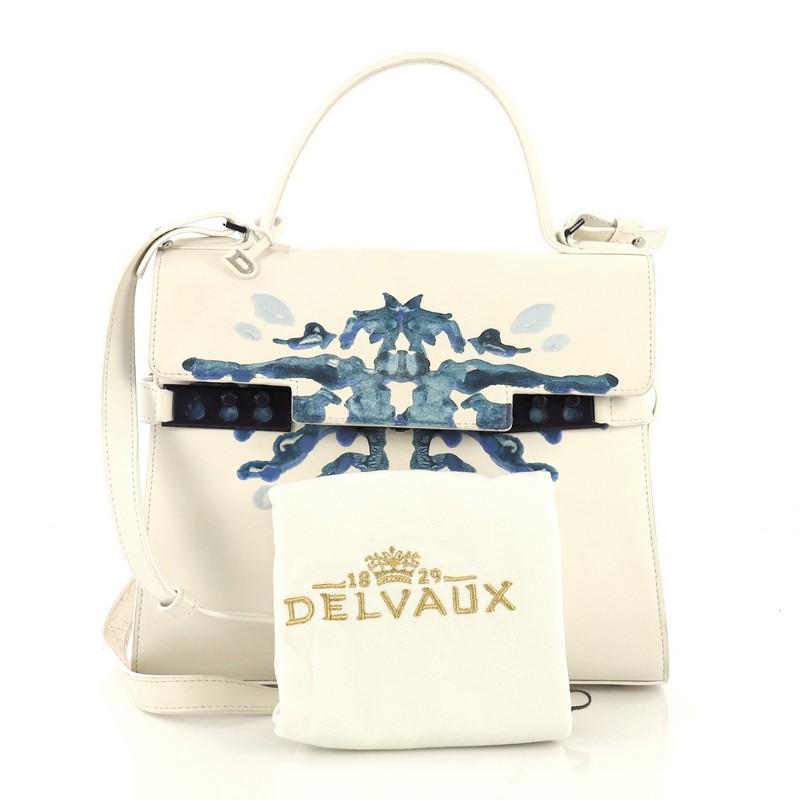 This Delvaux Tempete Top Handle Bag Hand Painted Leather MM, crafted from white hand painted leather, features leather top handle, protective base studs, and silver-tone hardware. Its flap opens to a white and blue leather interior with side zip and