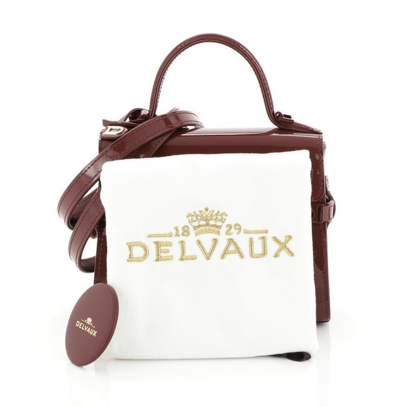 This Delvaux Tempete Top Handle Bag Patent Micro, crafted from red patent leather, features a leather top handle, protective base studs, and gold-tone hardware. Its flap opens to a neutral leather interior with side slip pocket. 

Estimated Retail