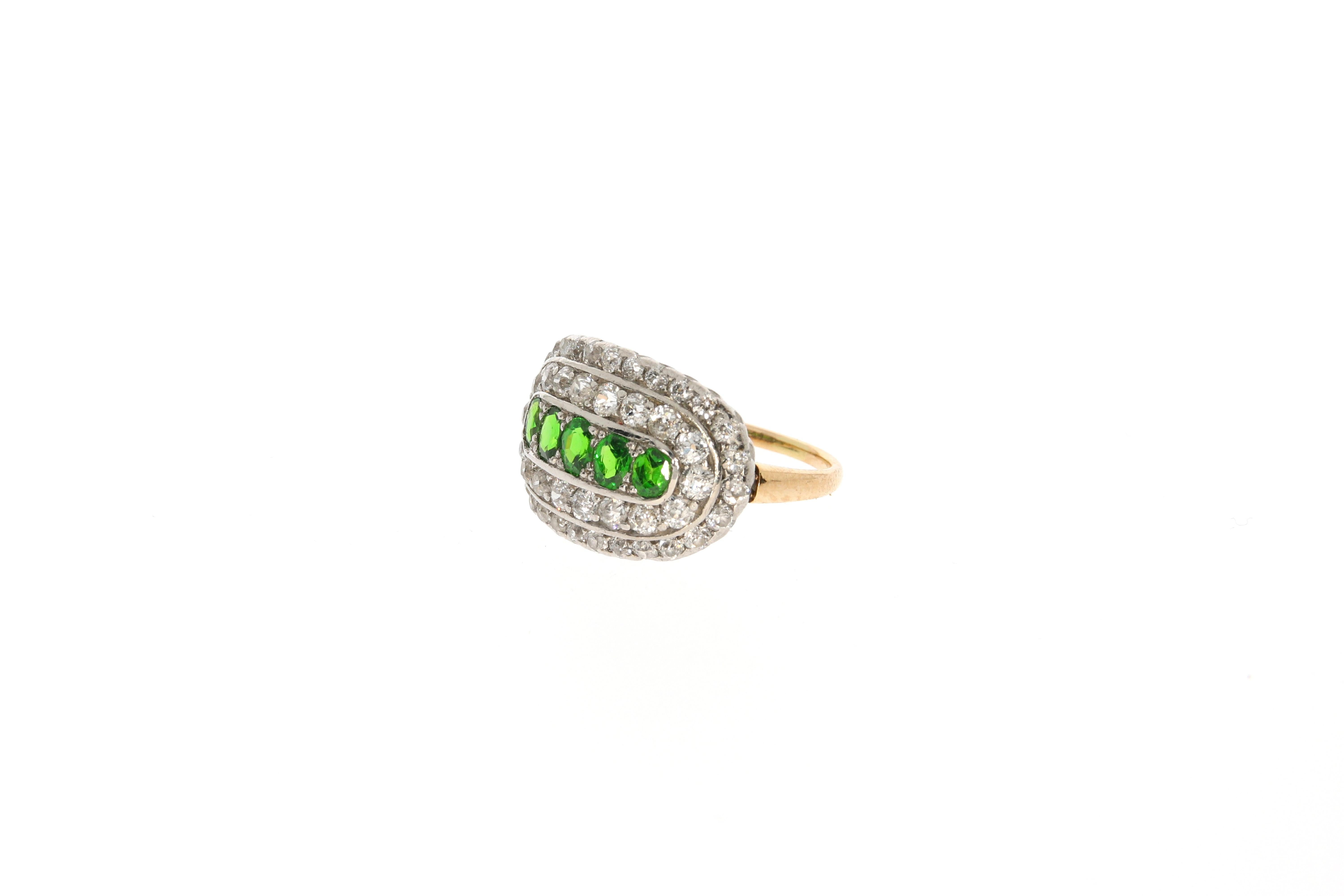 A beautiful ring set with 5 green demantoid (in total approx.: 0.85 ct) within two bands of old mine cut diamonds (in total approx.: 1.14 ct). The refined setting is made of platinum, whereas the ring itself is yellow gold. 
Ringsize: 50/51