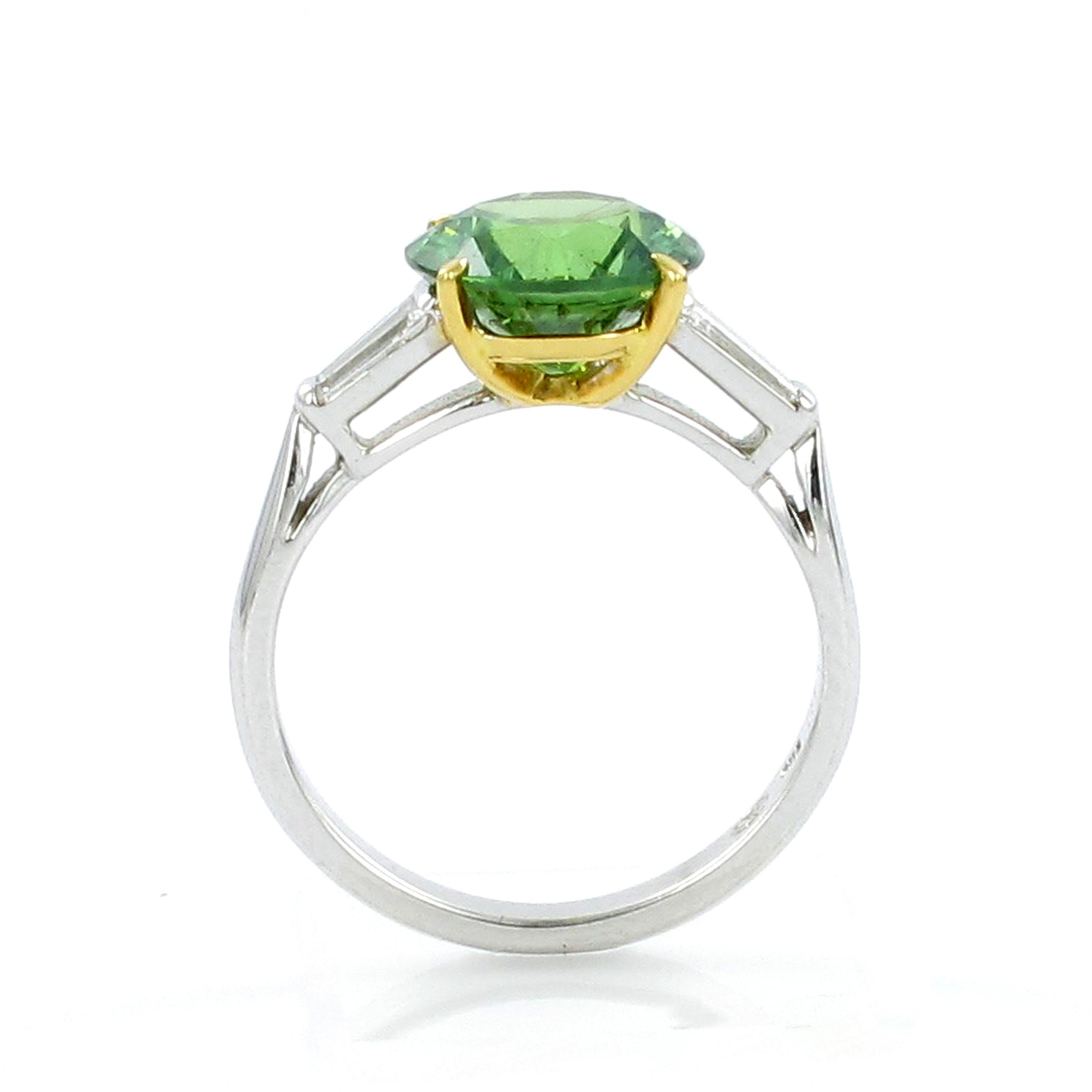 Classic solitaire ring in white gold 750. Center set in four yellow gold prongs with a rare Brazilian demantoid garnet of 3.01 ct. The round brilliant cut gem measures 9.05 mm in diameter. Demantoid garnet is a green variety of andradite garnet