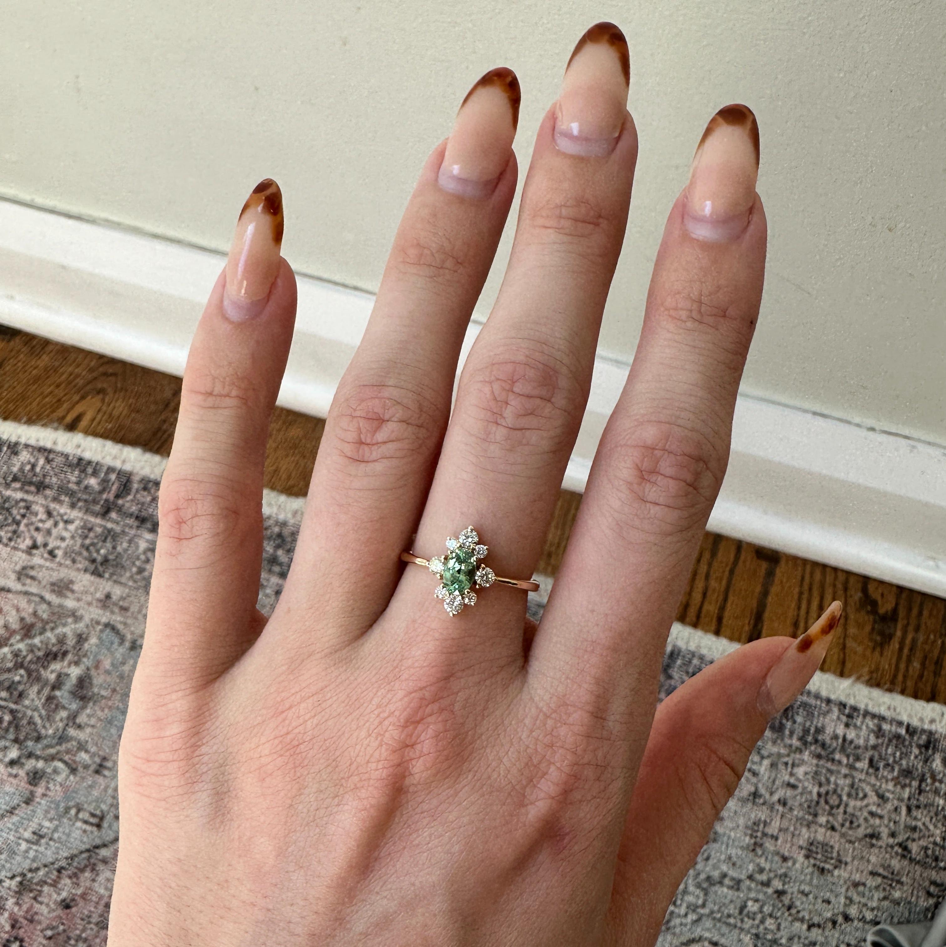 Elegant and captivating, this ring features a stunning 0.63 carat Demantoid gemstone surrounded by a halo of sparkling natural earth mined diamonds, all set in solid 14K gold. Perfect for any occasion, this ring is both timeless and