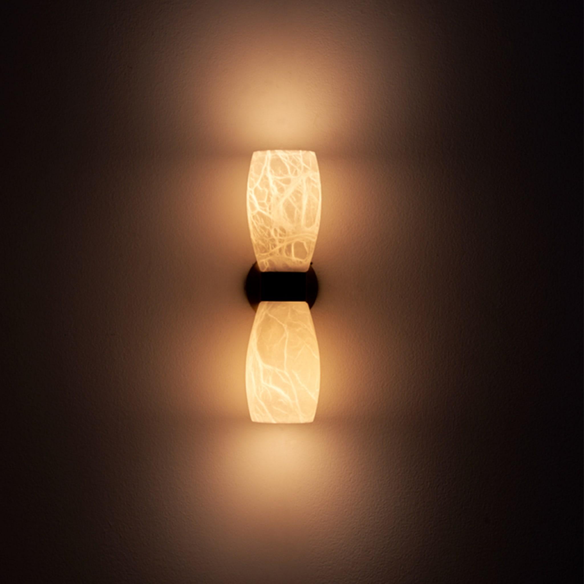 Demetra wall sconce, inspired by the mid-century style, combines the French gold and mat black finishes with alabaster to create a mesmerizing display. The ethereal glow emitted by the illuminated cups seems to hover in the air, casting a gentle,