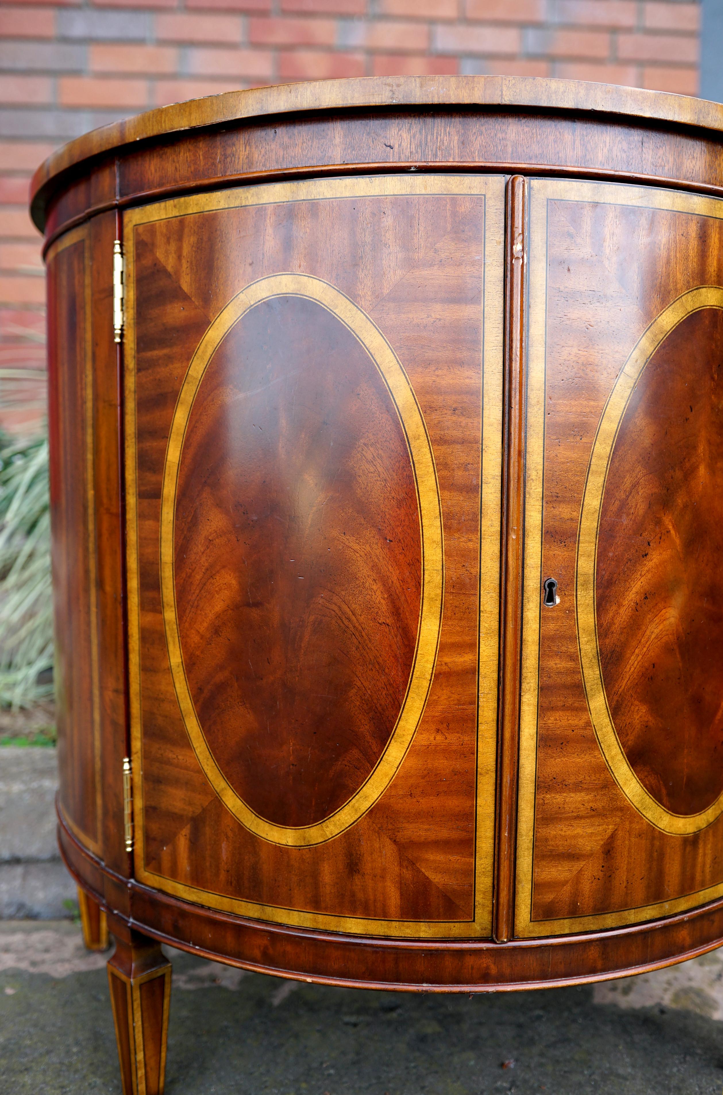 The shape and the finish of this Maitland Smith demilune cabinet of rich mahogany burl is sublime. The piece is a chiffonier, inspired by the French cabinet that came into use in the mid-1700s in France. They were used to store 
