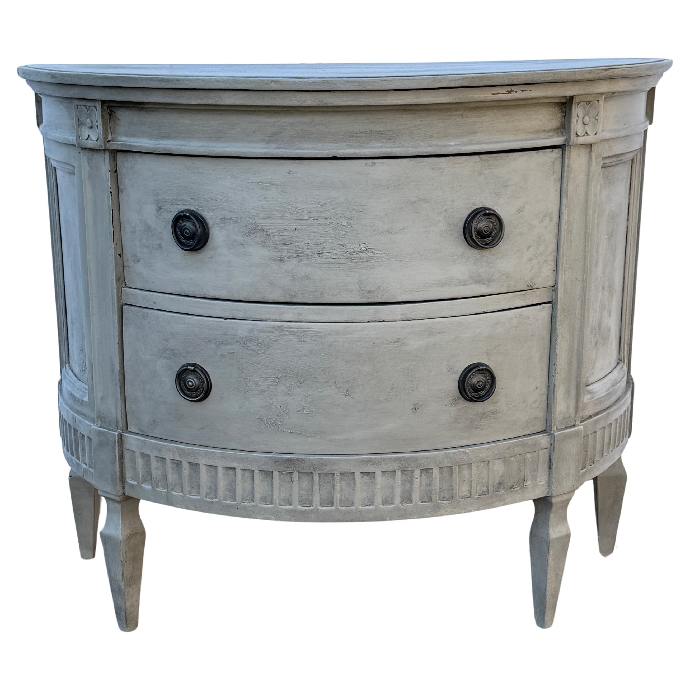 Swedish Gustavian Style Painted Commode Chest of Drawers

This classic Swedish style two drawer carved and hand painted neutral gray toned demi-lune chest or table has been constructed from solid wood. Wonderful details on this piece including a