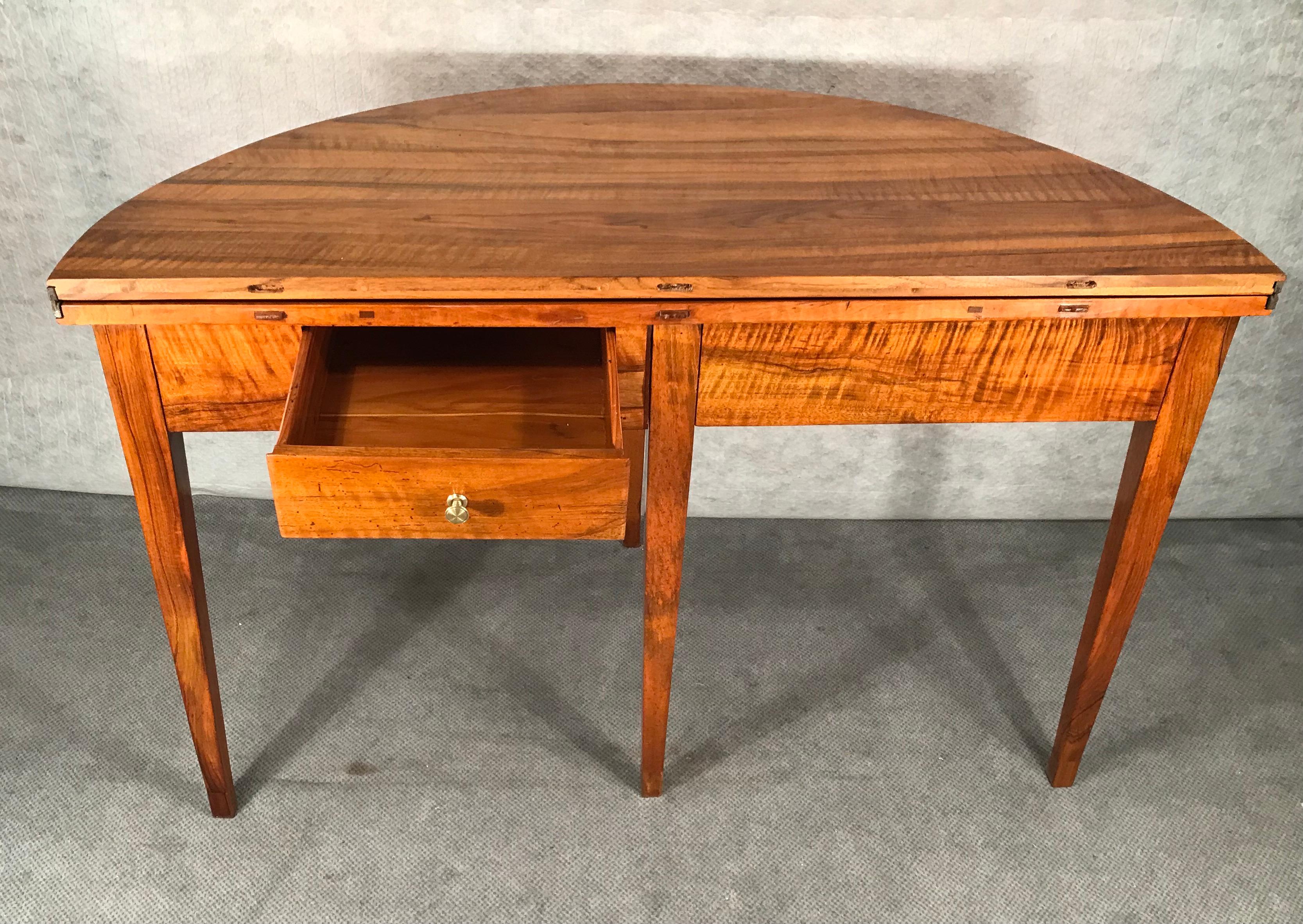 This elegant Demi-lune walnut table was made during the Biedermeier period in Southern Germany. It dates back to 1820. The table has a beautiful walnut veneer on top, apron and legs. There are two drawers in the apron. Your could easily use this