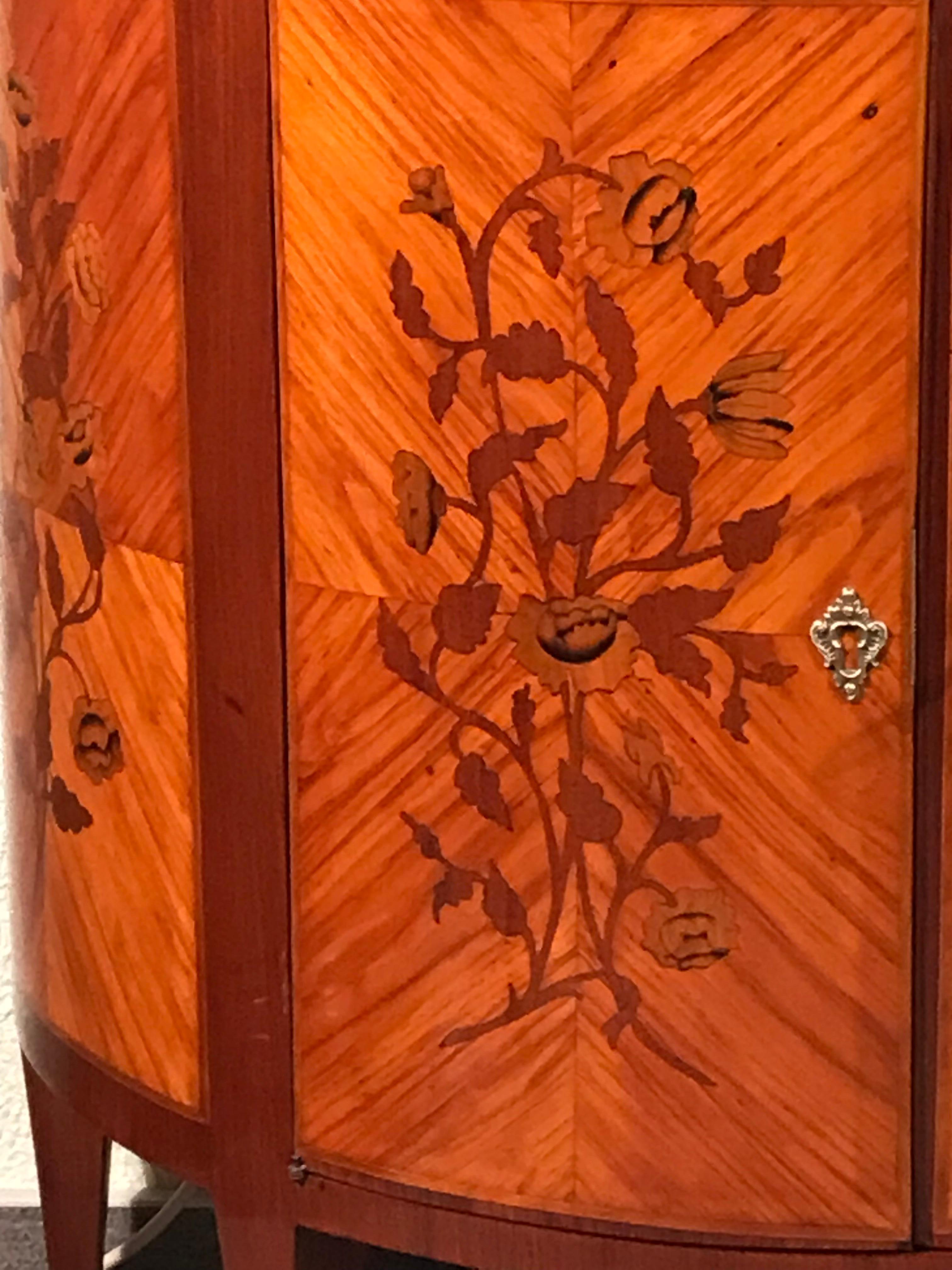 This Napoleon III Demi Lune cabinet is of exquisite quality. 
The half moon shaped cabinet has two doors and one central drawer. It has a very pretty kingwood veneer with a gorgeous flower marquetry on doors and sides. Behind the doors is one