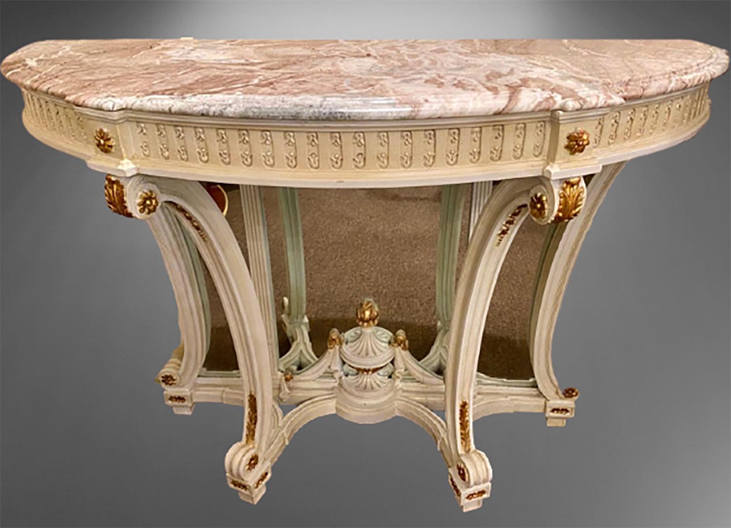 Demilune Hollywood Regency style marble-top consoles or serving tables. A pair of fine Louis XVI style custom quality parcel gilt and crème paint decorated beveled mirror back consoles, serving or sofa tables. With sprayed legs and a carved