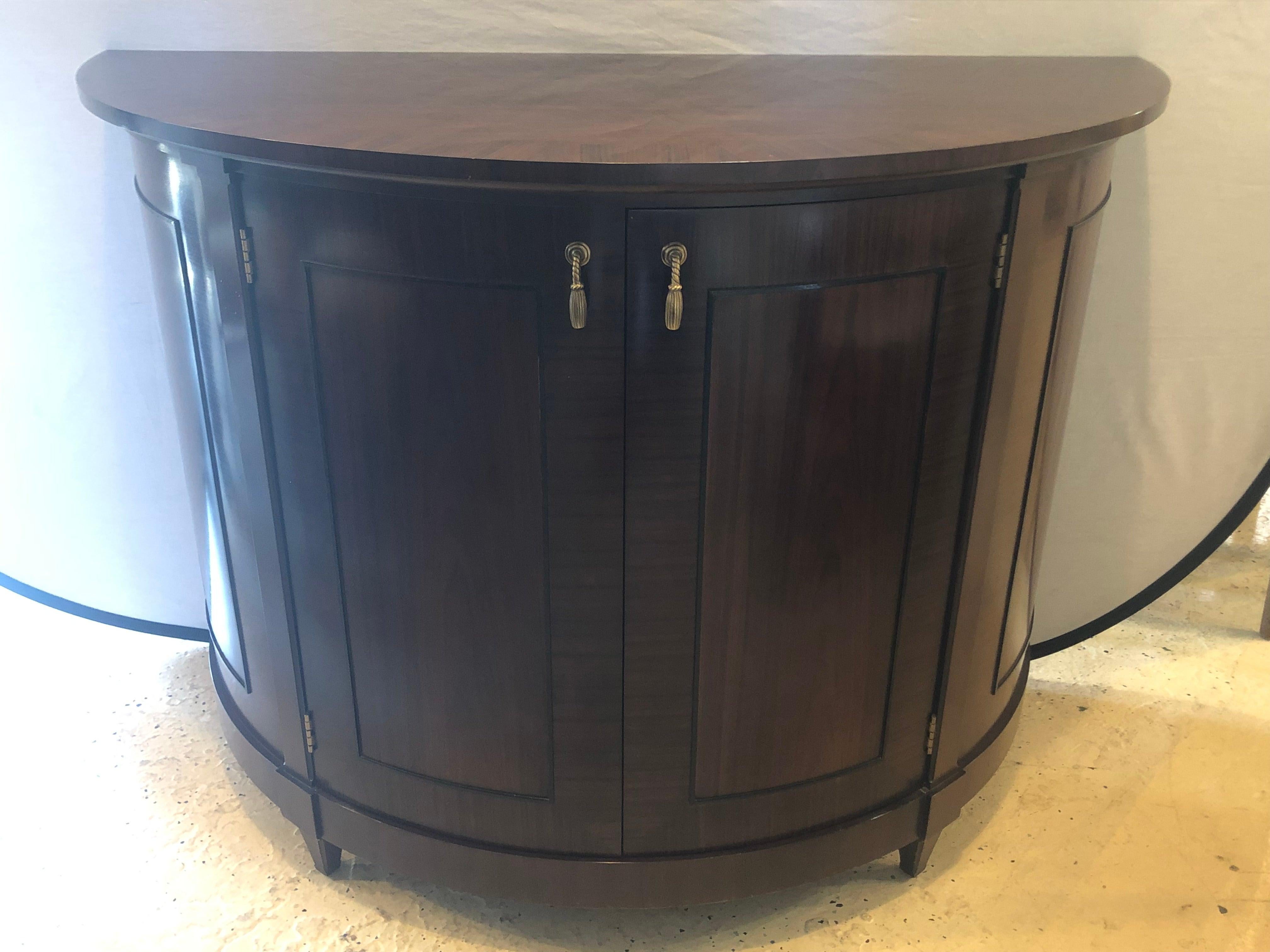 A baker flame mahogany sideboard or serving cabinet with ebony inlays. This Georgian inspired Baker Furniture Company serving cabinet or sideboard has a deep demilune form with a fitted interior. The back bearing the Baker tag leading to a sharp and