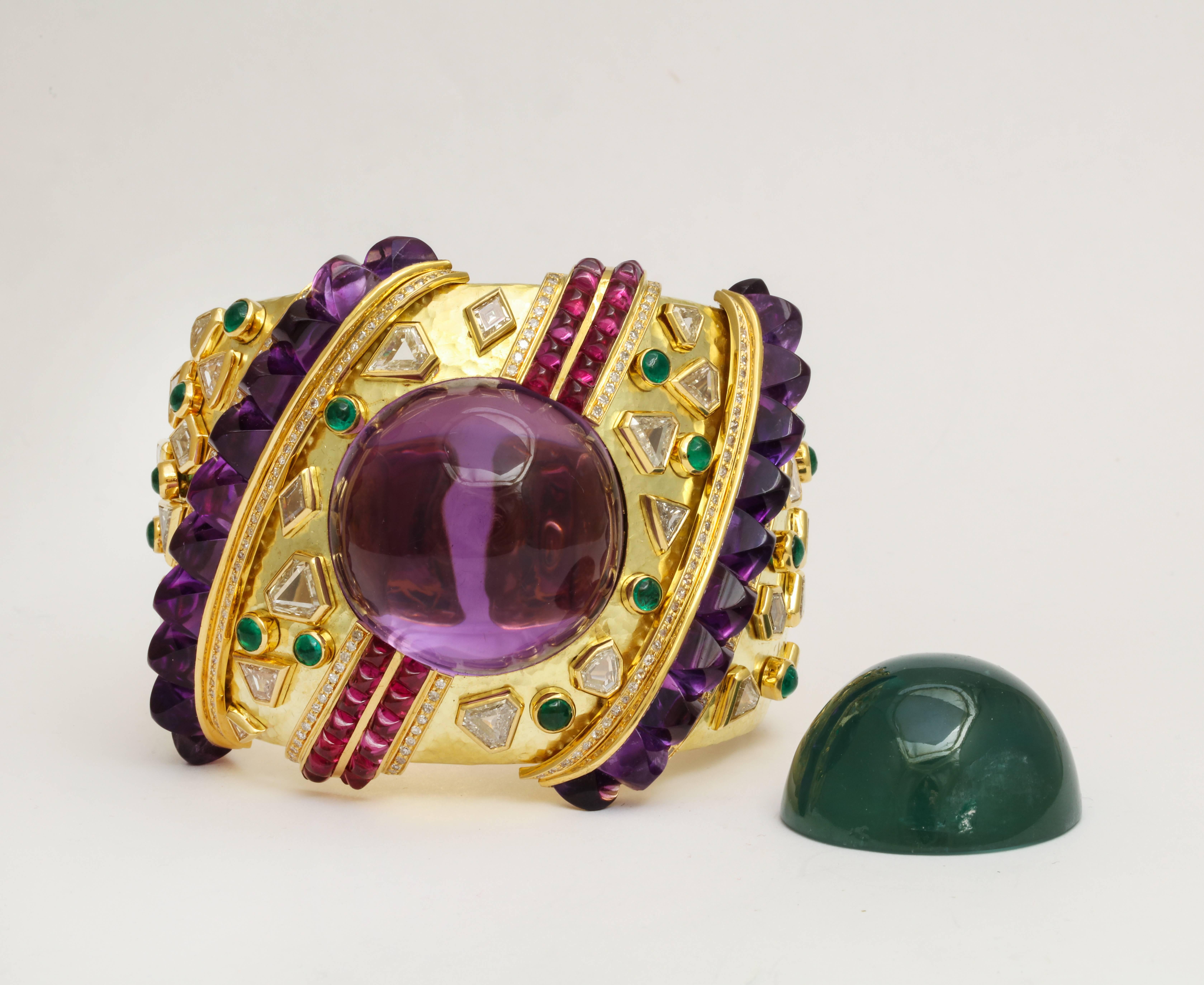 A magnificent 1980s one-of-a-kind Demner convertible bracelet of hammered 18K gold set with numerous large geometric cut diamonds and cabochon emeralds, centered by a large cabochon amethyst stone (154.31 cts) which can be switched to a natural