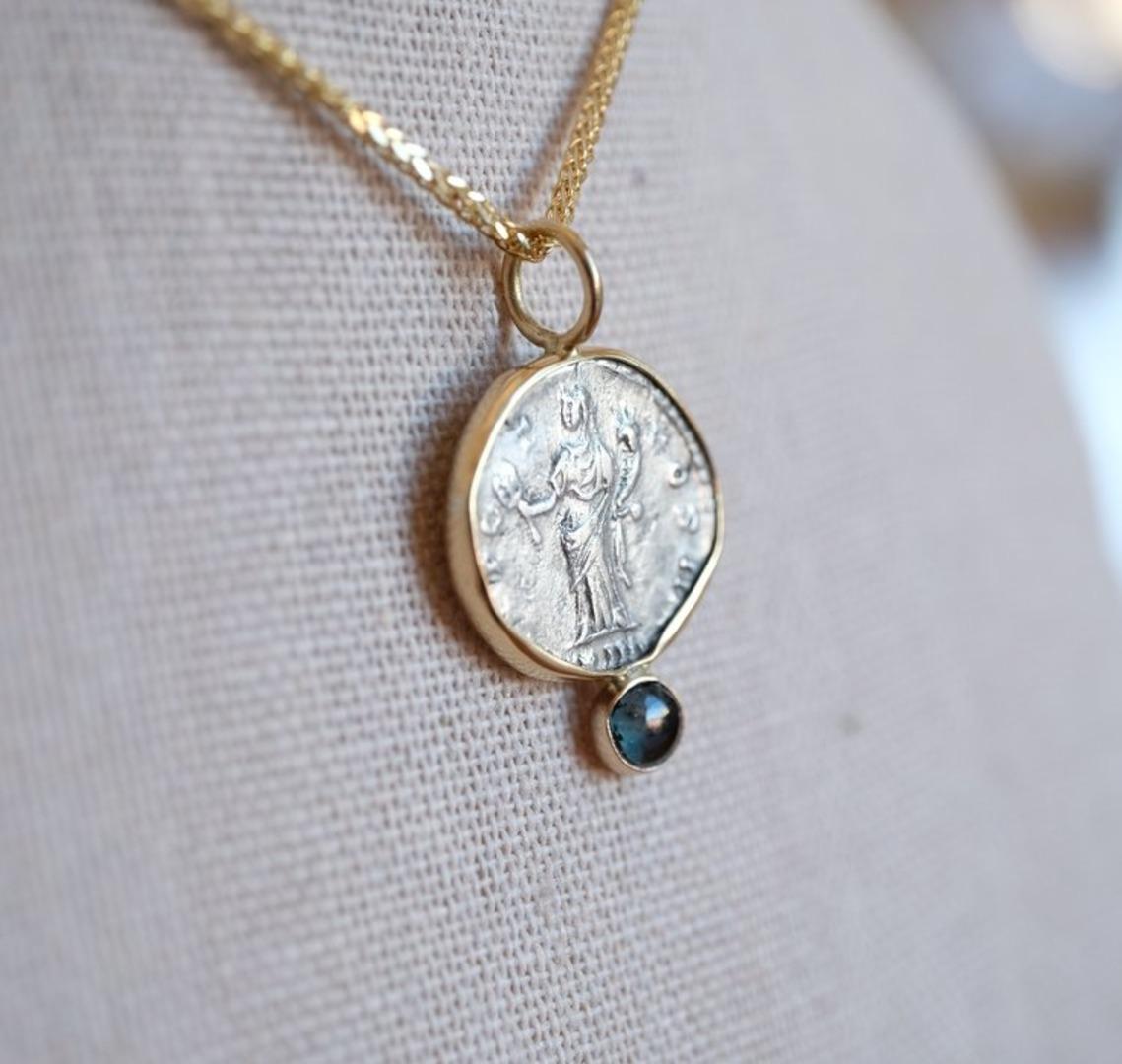 Gorgeous coin with a beautiful sapphire at the bottom of the piece. The bezel was hand crafted from 18k gold to fit this coin.

To appreciate the pendant's size, the relief of the coin and the shape of the bail, see the picture showing the coin next