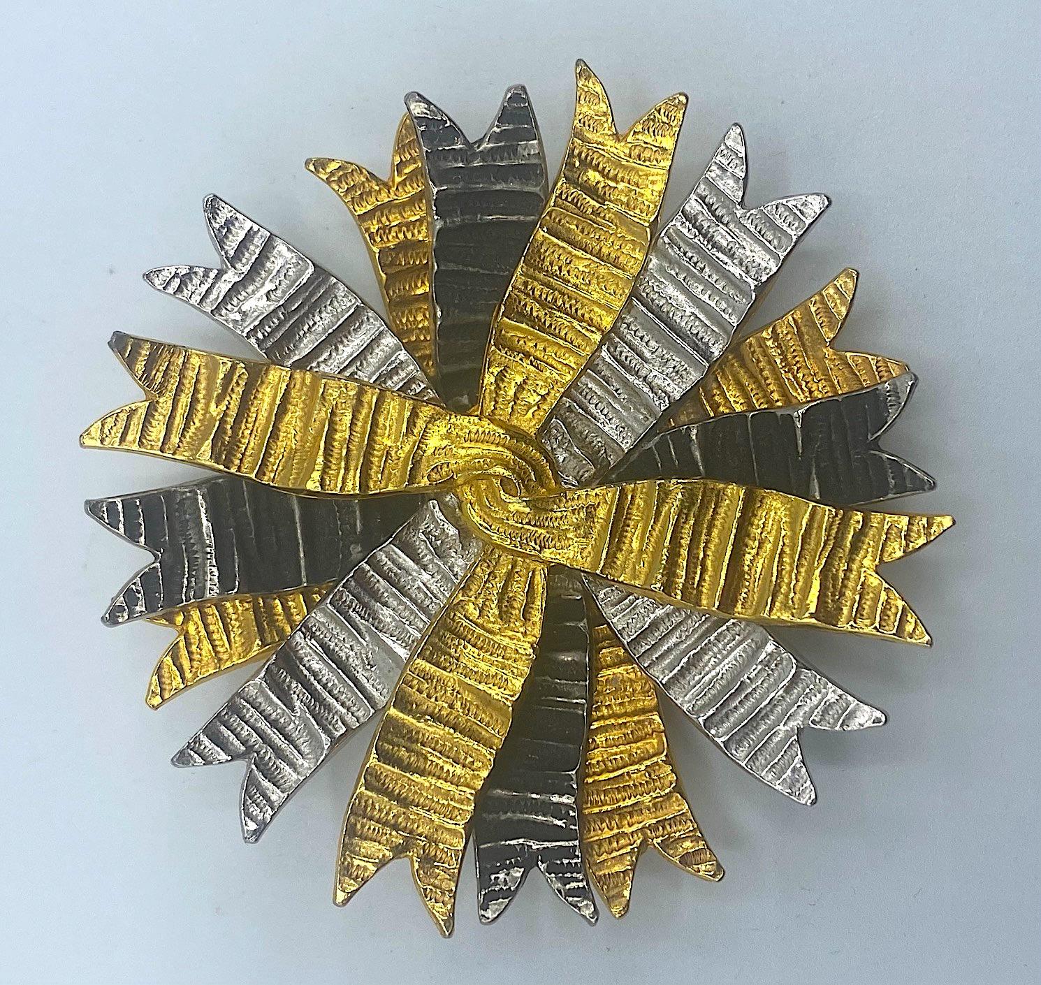 This DeNicola brooch is meticulously cast and executed. It is comprised of four layers of cast rippling and twisted ribbon in gold plate, silver plate and patinated charcoal black finish. The brooch is a complex and time consuming piece to produce