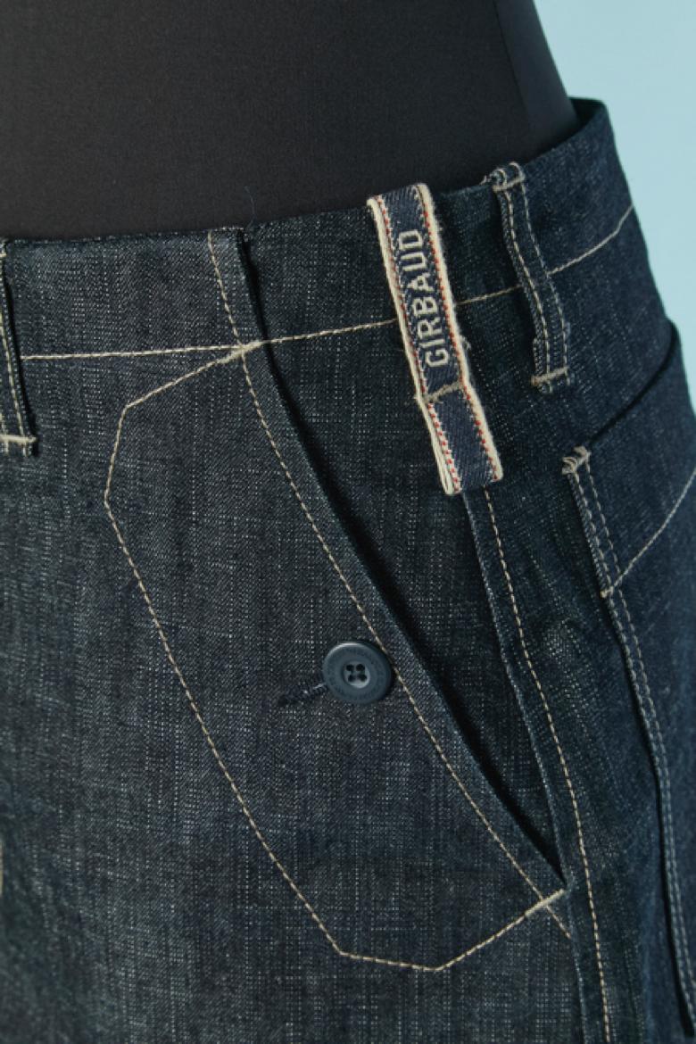 Gonna in denim e nylon kaki. Composizione del tessuto Fabrice: 52% nylon, 38% poliestere, 10% spandex. Coulisse sul fondo della gonna. Chiusura con bottoni, asole e cerniera nella parte centrale del davanti. 3 tasche sul davanti e 2 sul retro.