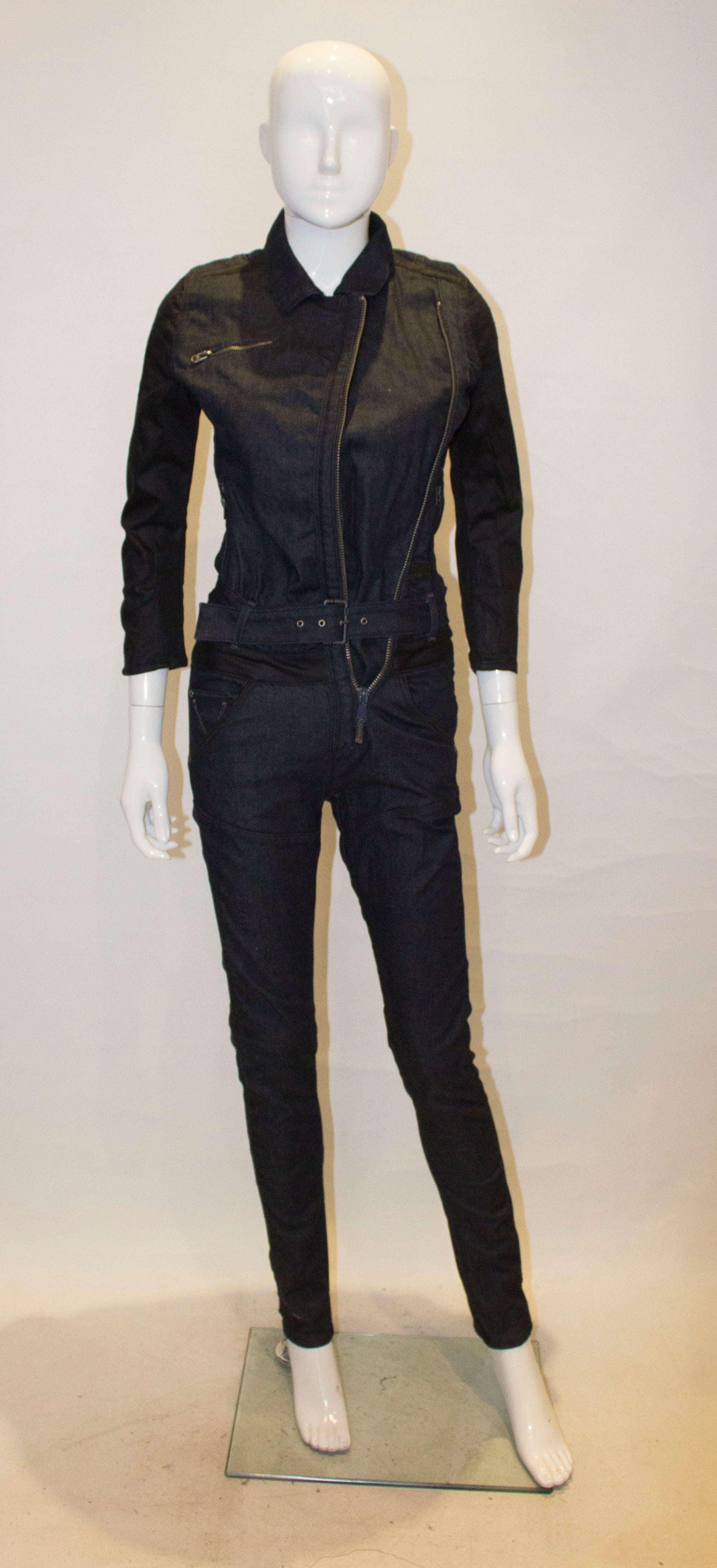 A fun denim jumpsuit for Spring , Summer. In  a heavy dark denim the jumpsuit has a front zip opening, self fabric belt, and pockets on the back.