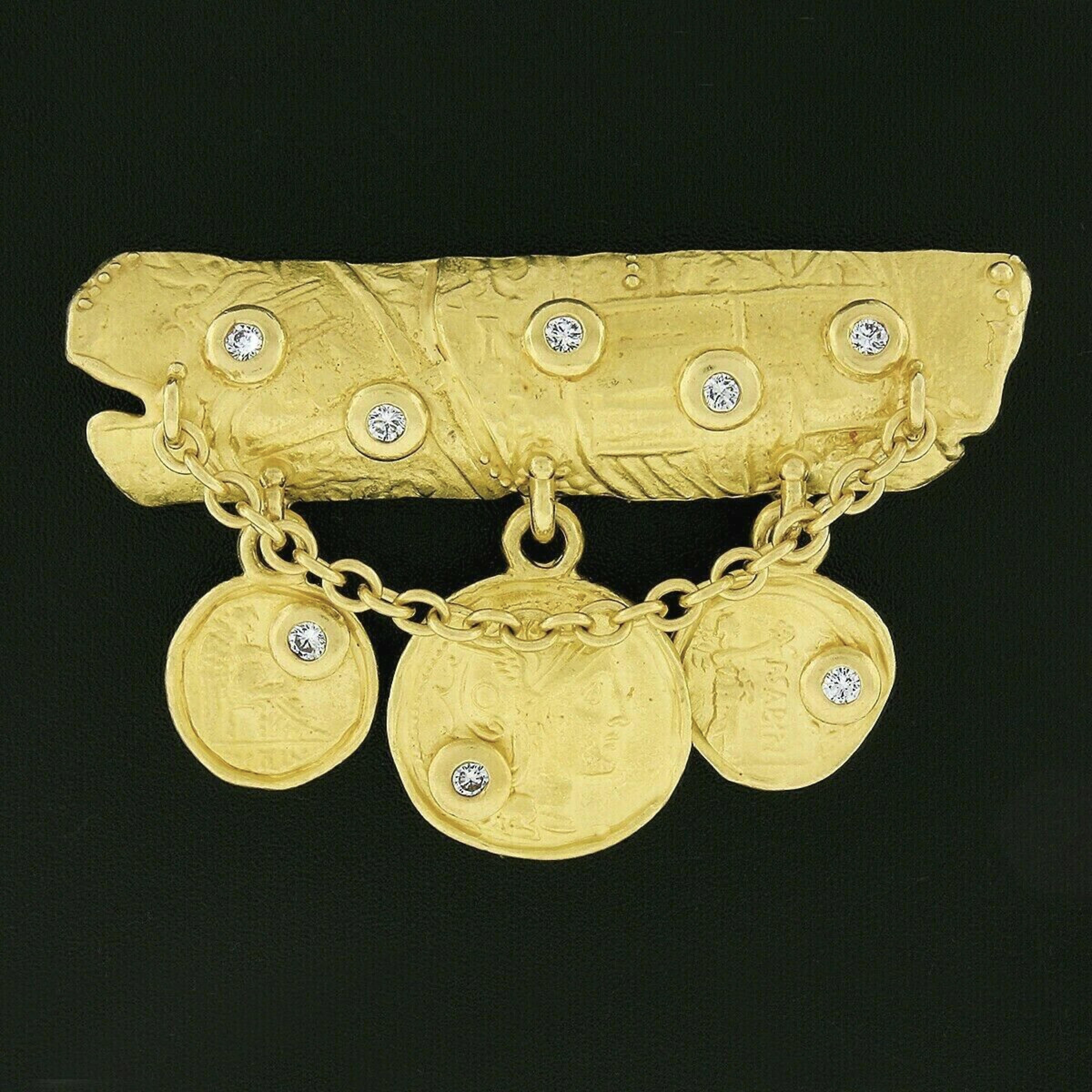 Here we have a magnificent pin brooch designed by Denise Roberge that is crafted in solid 22k yellow gold. It features a bold domed bar at its top part adorned with a cable chain and three detailed ancient coins gently dangling below, with