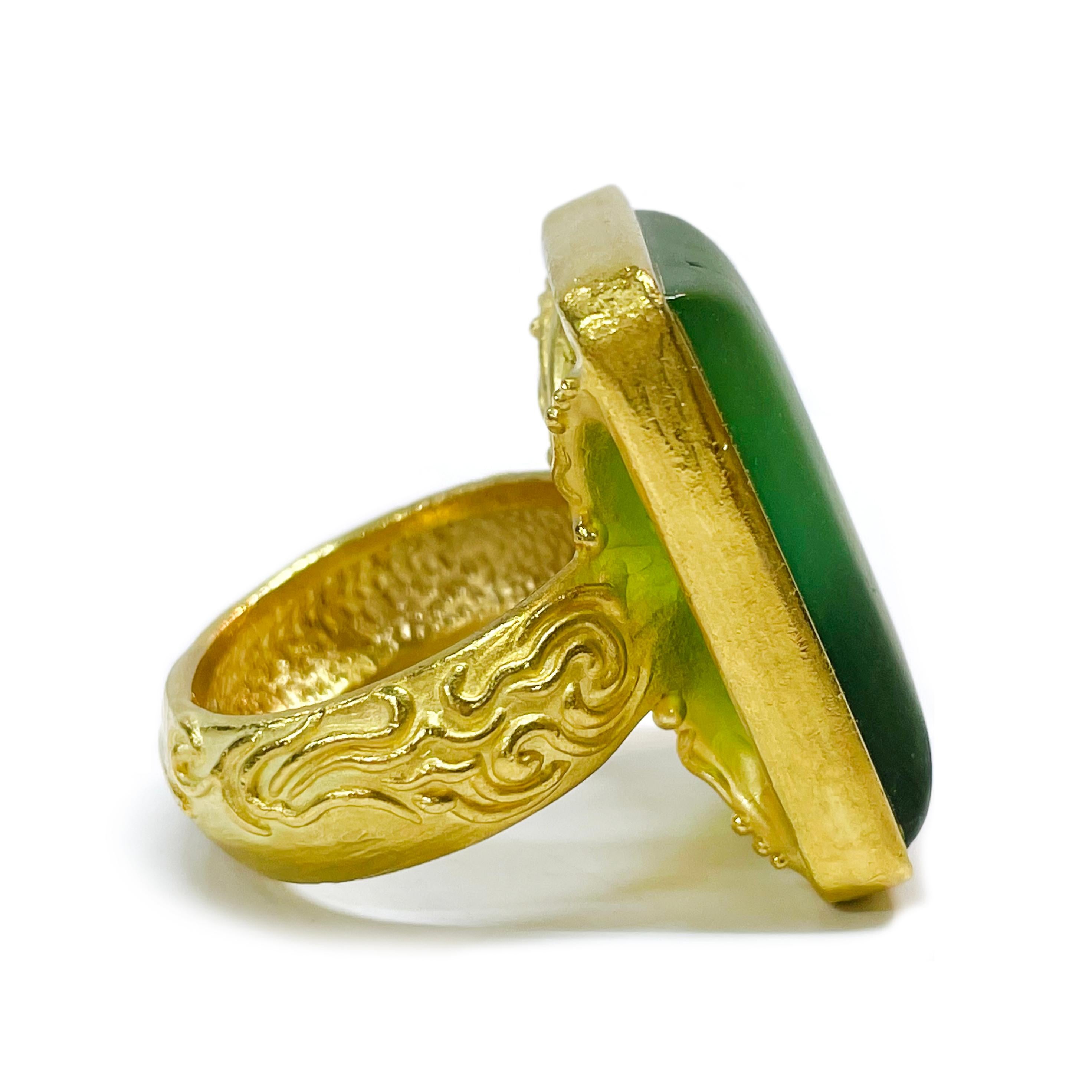 Denise Roberge 22 Karat Yellow Gold Agate Ring. The heavyweight ring features a rectangular opaque green Chalcedony cabochon measuring 20.3 x 26.4mm. The 8.24mm wide band has wave-like scroll detail on both sides. Stamped on the inside of the band