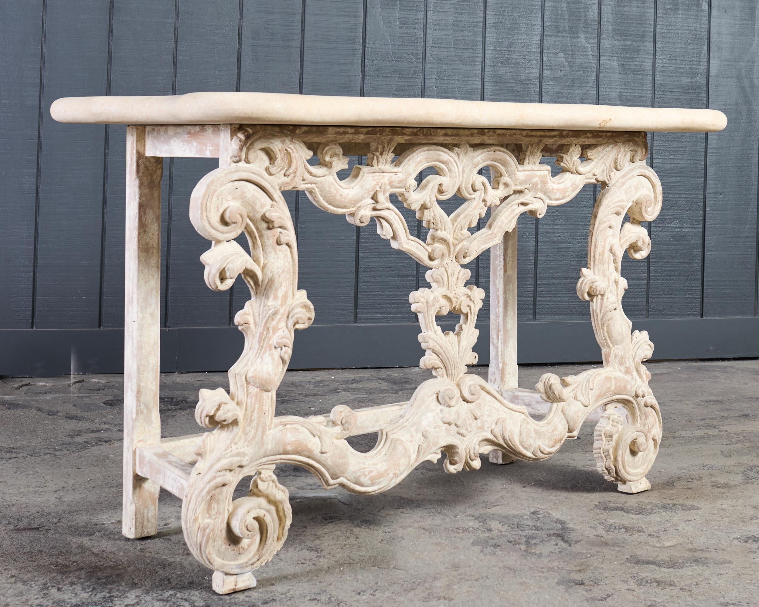 Opulent Spanish baroque style pietra stone top console table (model #DL-CN11) designed by Dennis and Leen, Hollywood, CA. The console features an intricately carved base crafted from beech. The base is decorated in the Baroque taste with gracefully